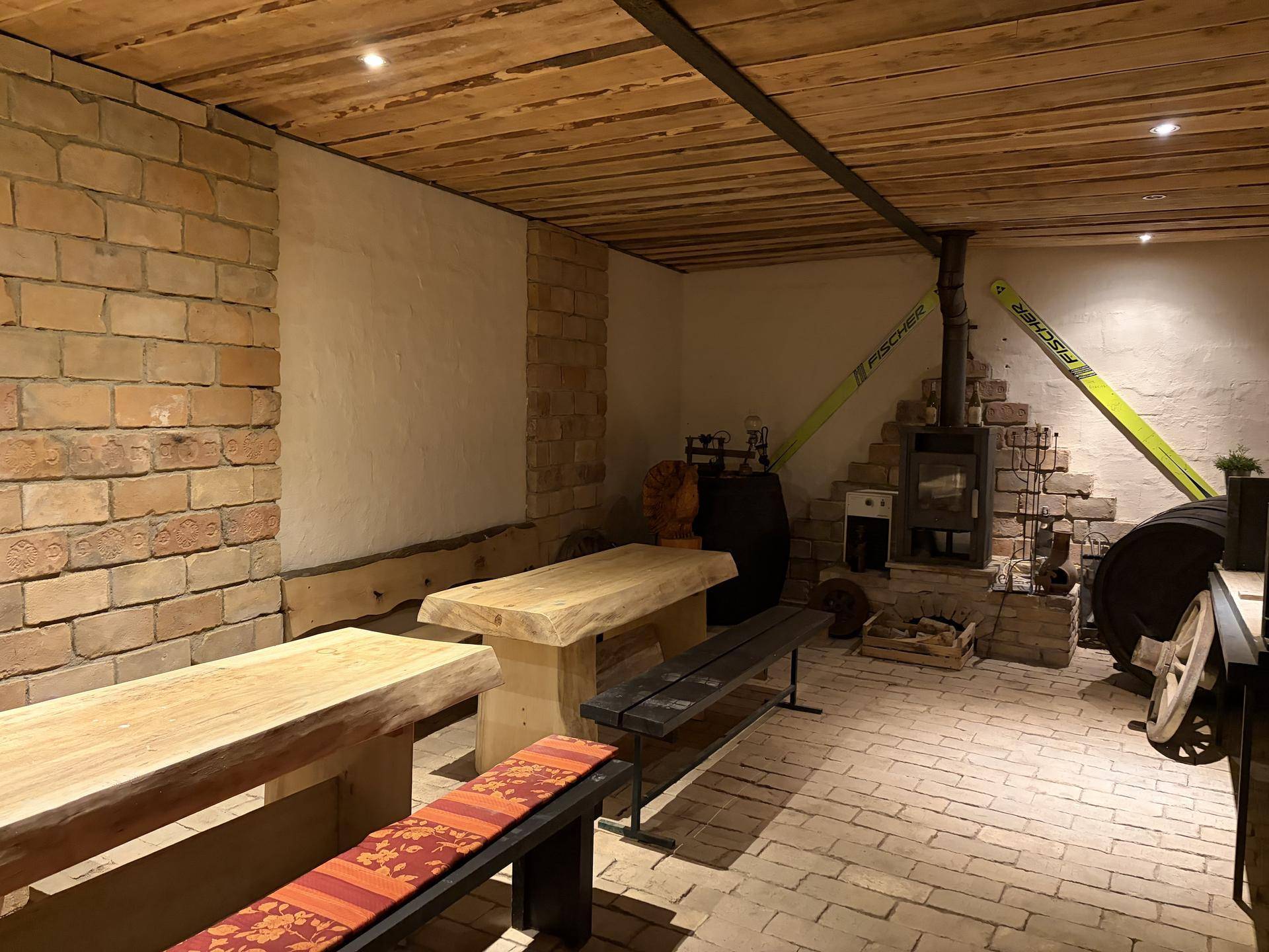 Gemütlicher rustikaler Raum mit Holzbänken, Kamin und Ziegelboden, ideal für gesellige Abende.