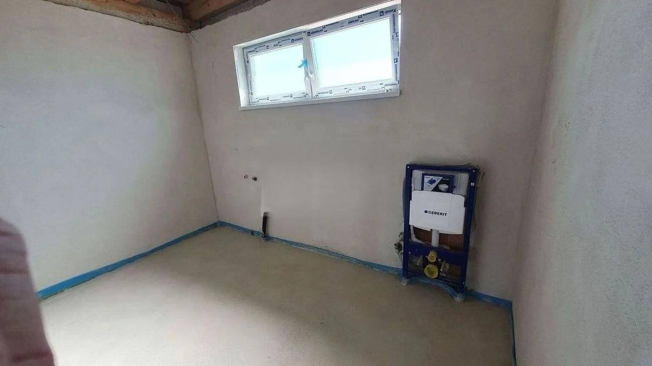 Unfertiges Badezimmer mit sichtbaren Installationen für Toilette und Waschbecken, bereit für den Ausbau.