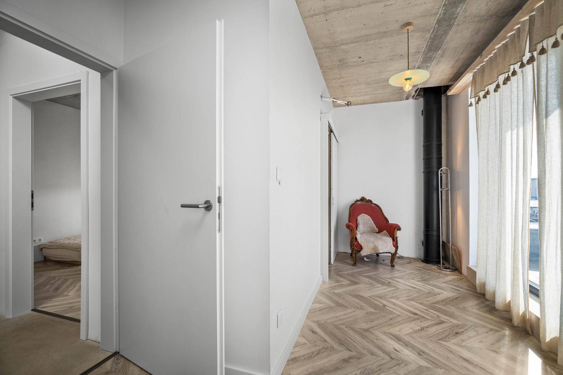 Heller Flurbereich mit Parkettboden, Betondecke und Zugang zu weiteren Räumen.