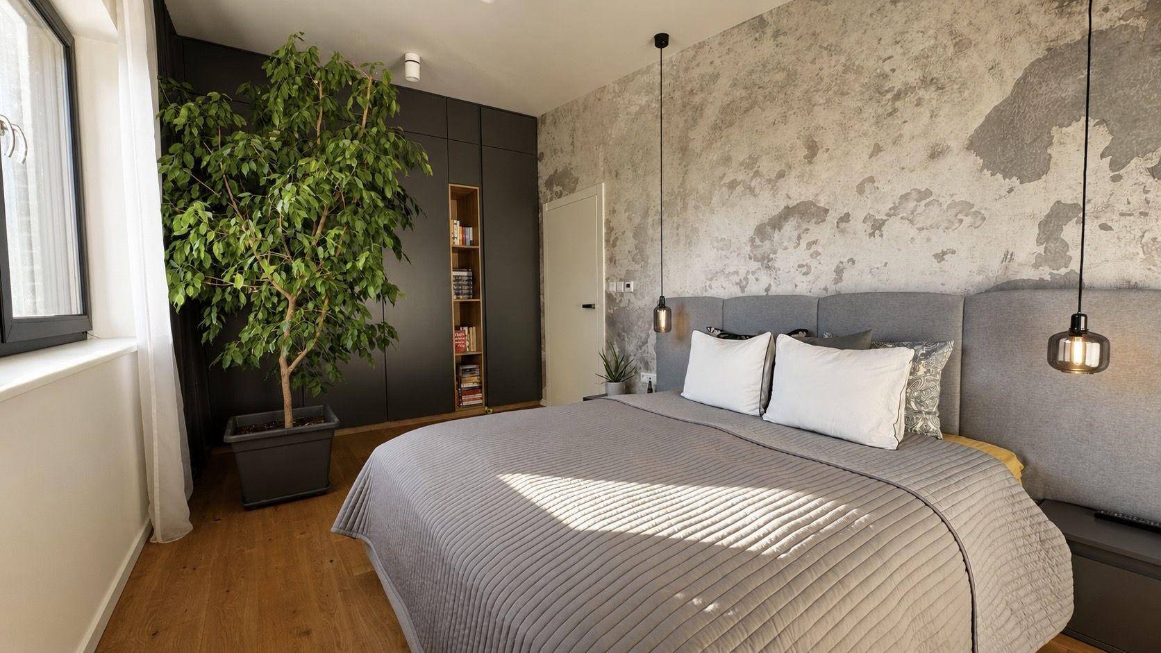 Modernes Schlafzimmer mit Doppelbett, dunklen Einbauschränken und einer strukturierten Akzentwand.