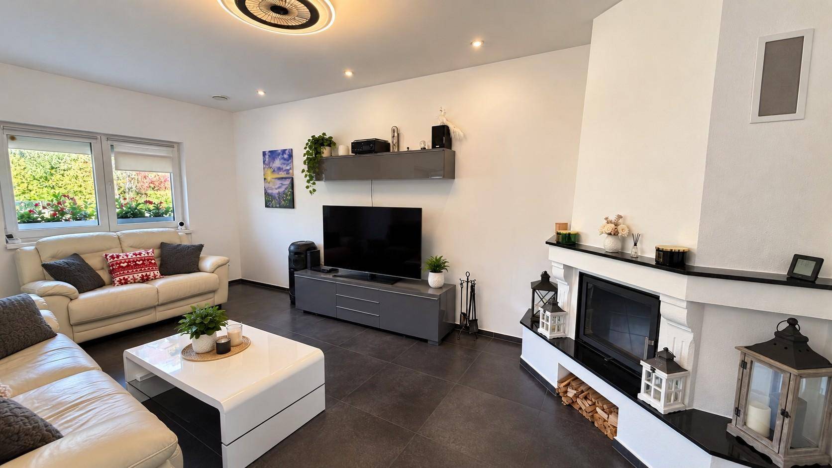 Helles Wohnzimmer mit Kamin, großem Fenster und gemütlicher Sitzecke.