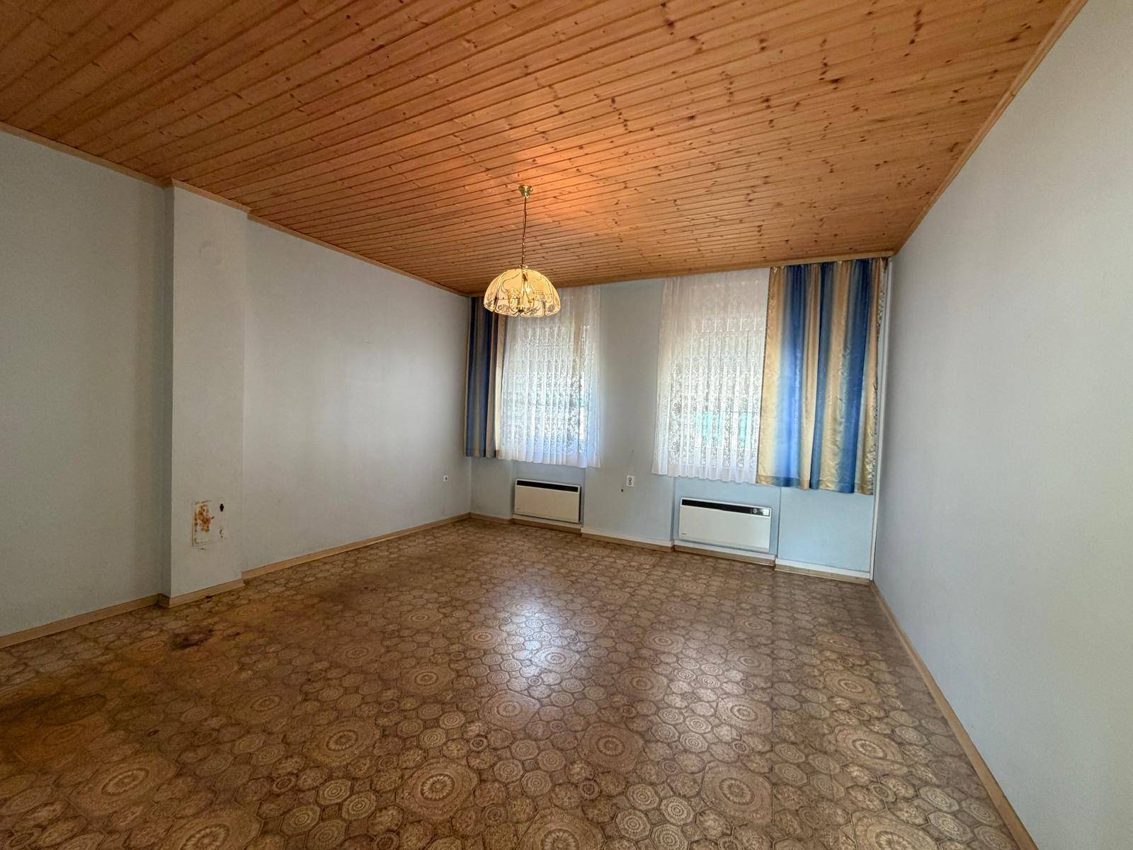Geräumiges Wohnzimmer mit gemustertem Linoleumboden und Holzdecke.
