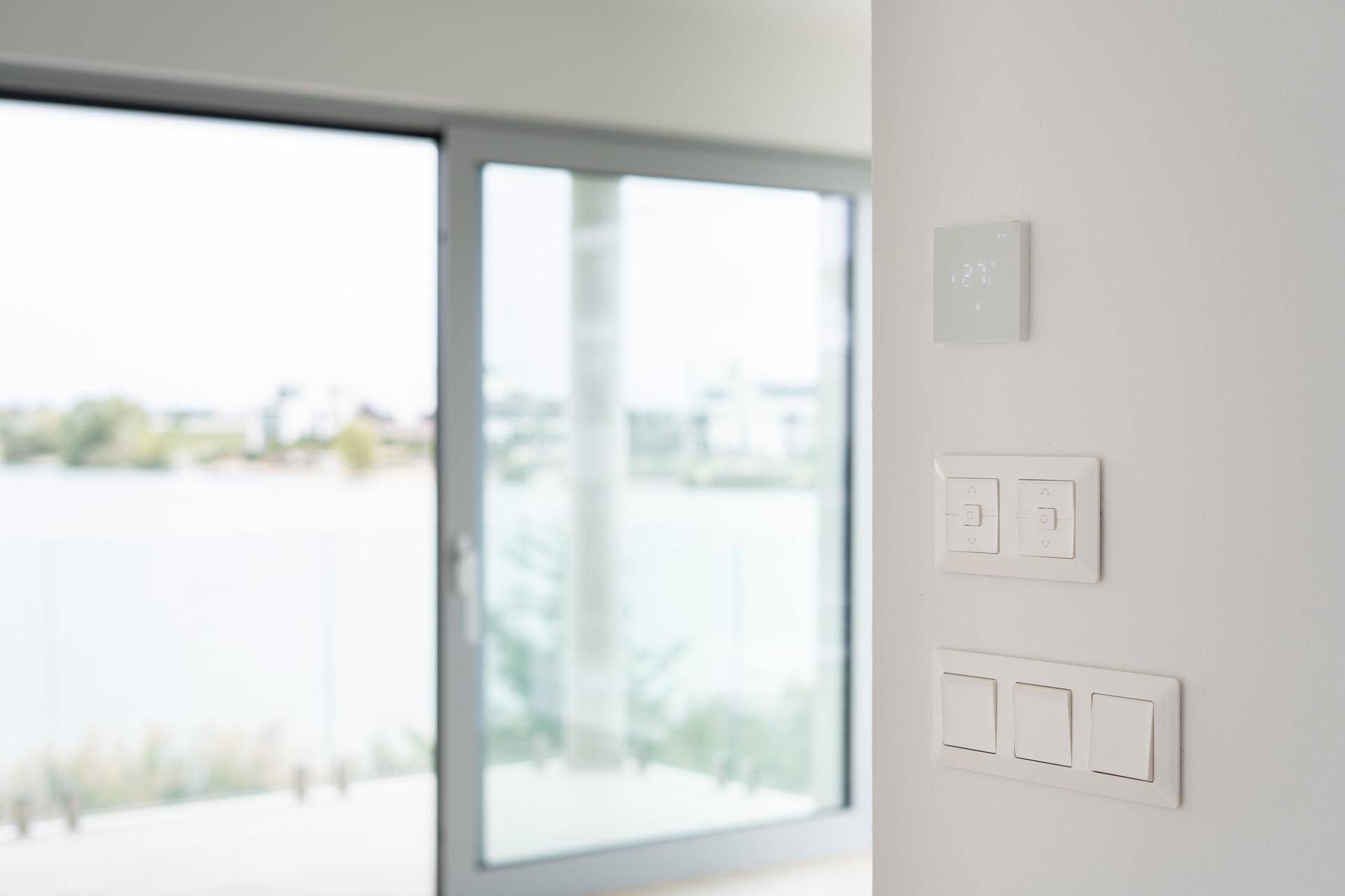 Moderne Lichtschalter und ein Thermostat an einer Wand mit Blick auf den See.