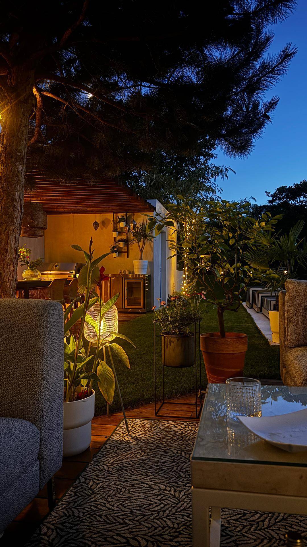 Gemütlicher Lounge-Bereich im Garten bei Nacht, stimmungsvoll beleuchtet mit Lichterketten.