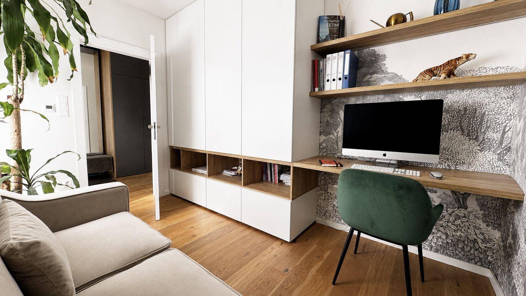 Helles Arbeitszimmer mit Schreibtisch, Computer, Regalen und einem bequemen Sofa.