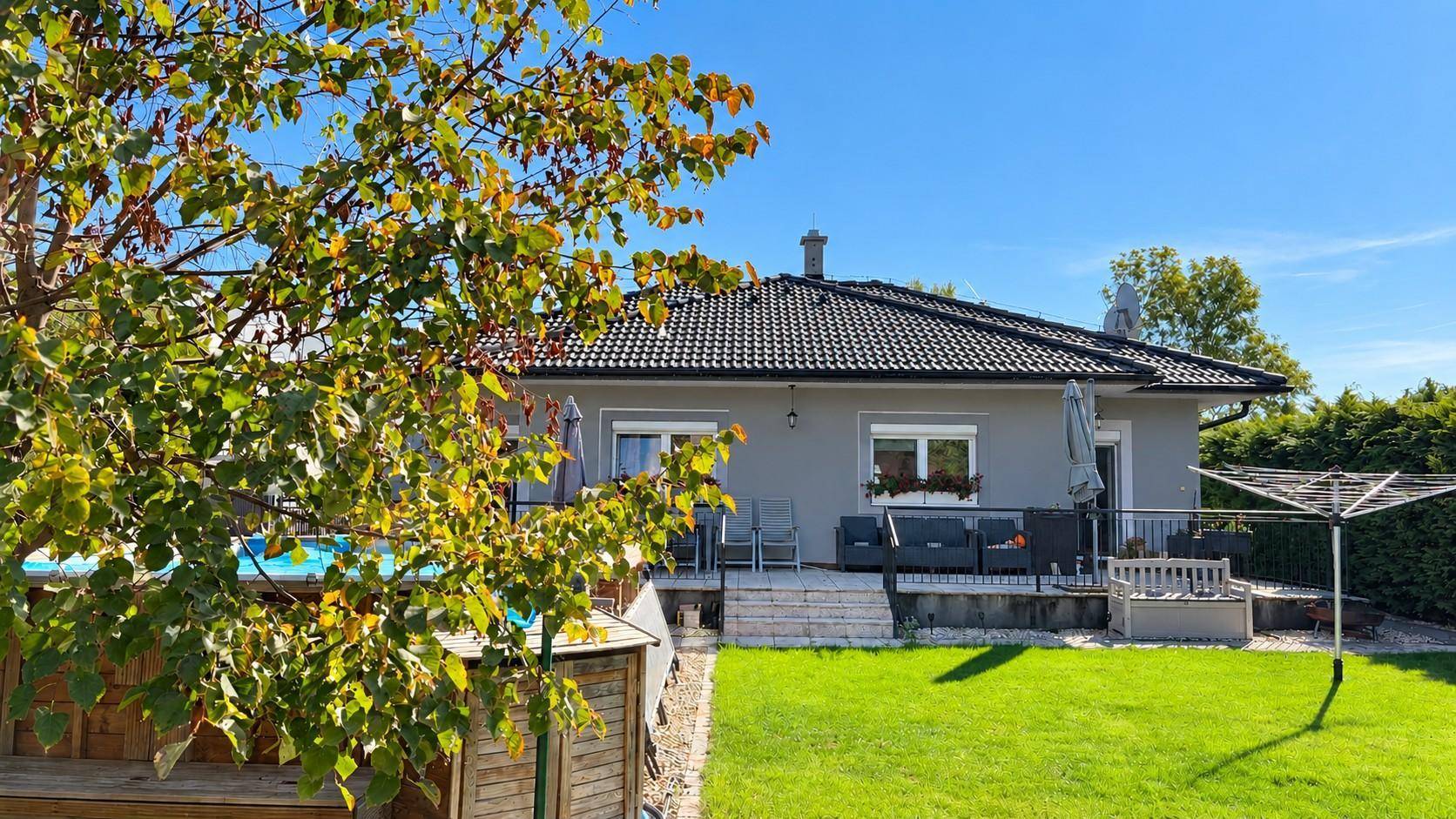 Sonniger Gartenbereich mit Pool und Terrasse hinter dem Einfamilienhaus.