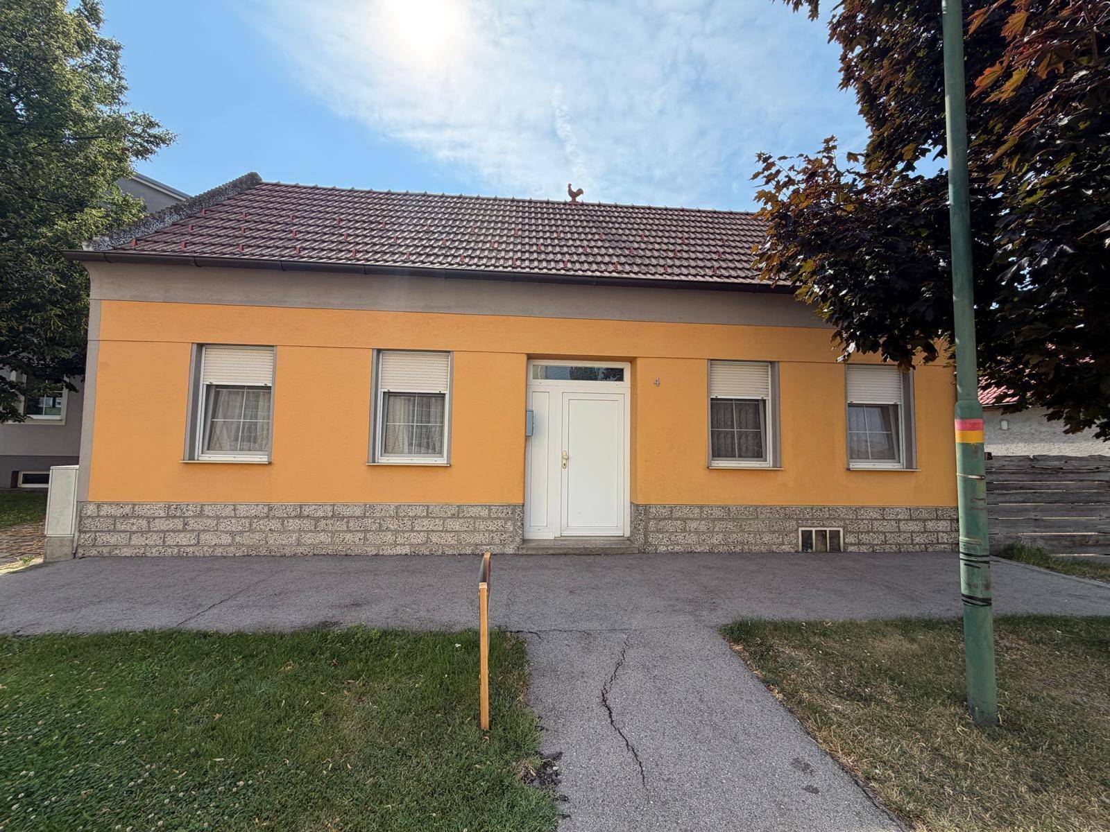 Vorderansicht eines Einfamilienhauses mit gelber Fassade und Satteldach.
