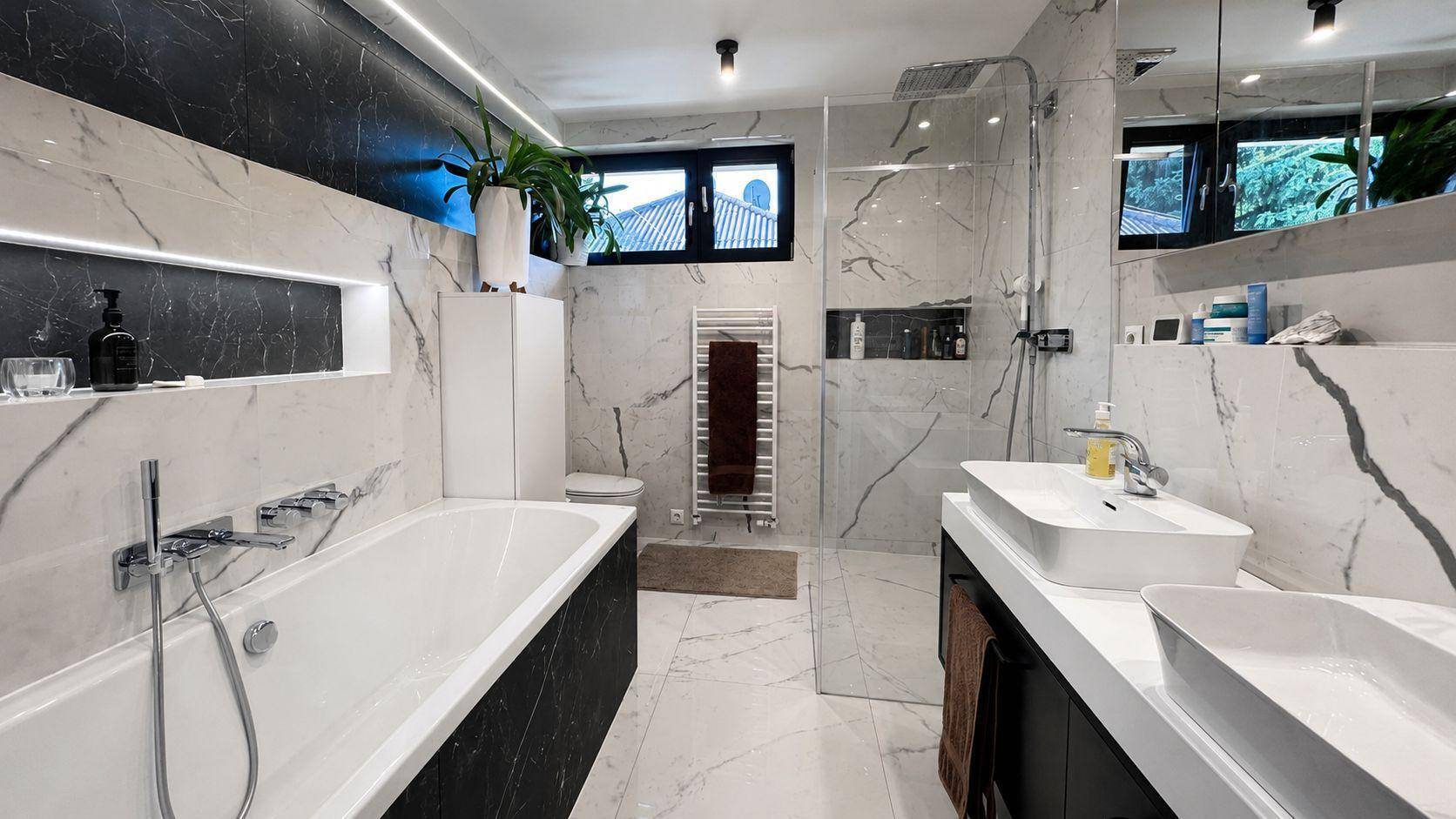 Luxuriöses Badezimmer mit Marmorfliesen, Badewanne, begehbarer Dusche und Doppelwaschbecken.