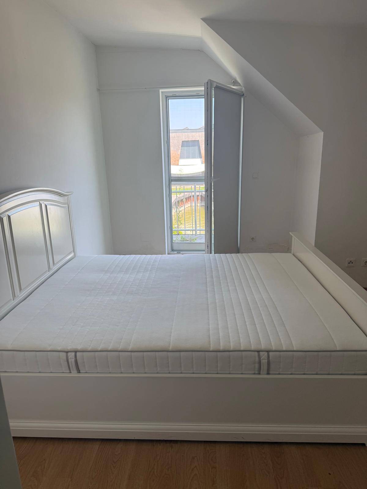 Schlafzimmer mit Doppelbett, Dachschräge und französischem Balkon.