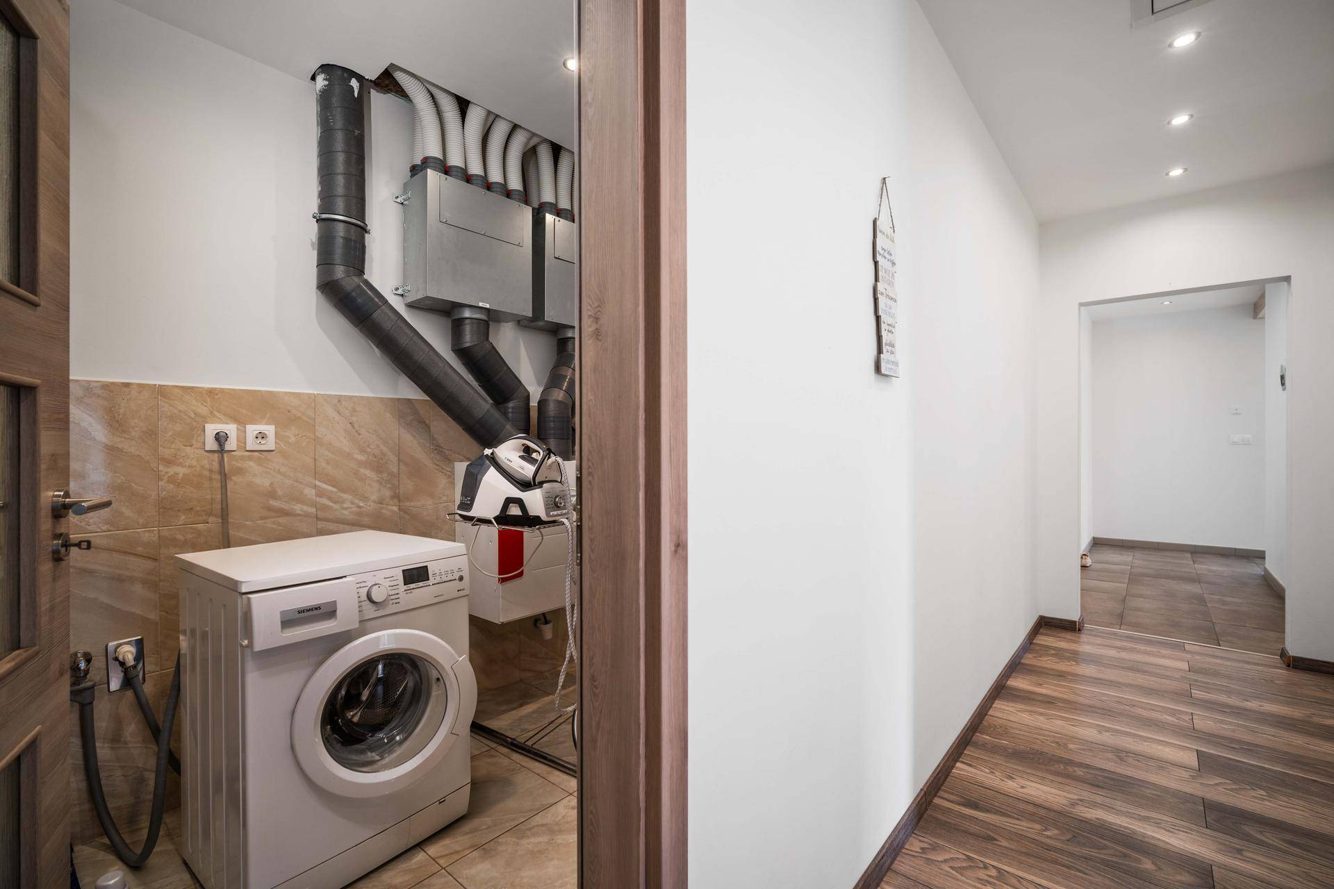 Funktionaler Hauswirtschaftsraum mit Waschmaschine und Lüftungsanlage.