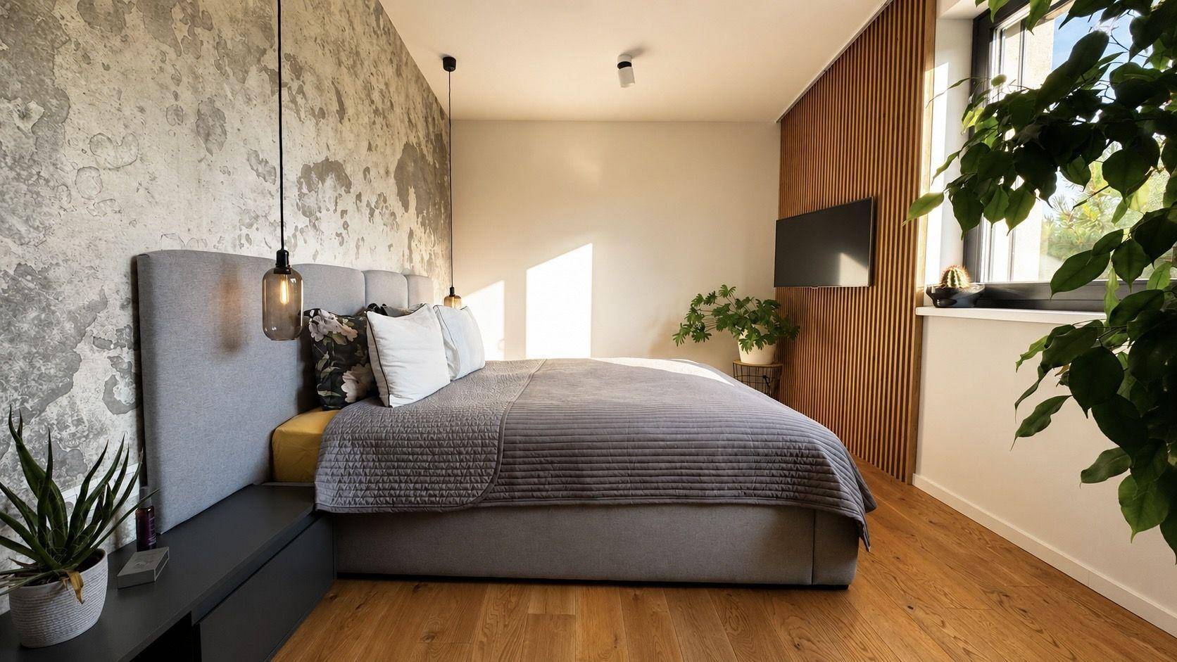 Stilvolles Schlafzimmer mit Doppelbett, Akzentwand und Holzlamellenwand mit integriertem Fernseher.