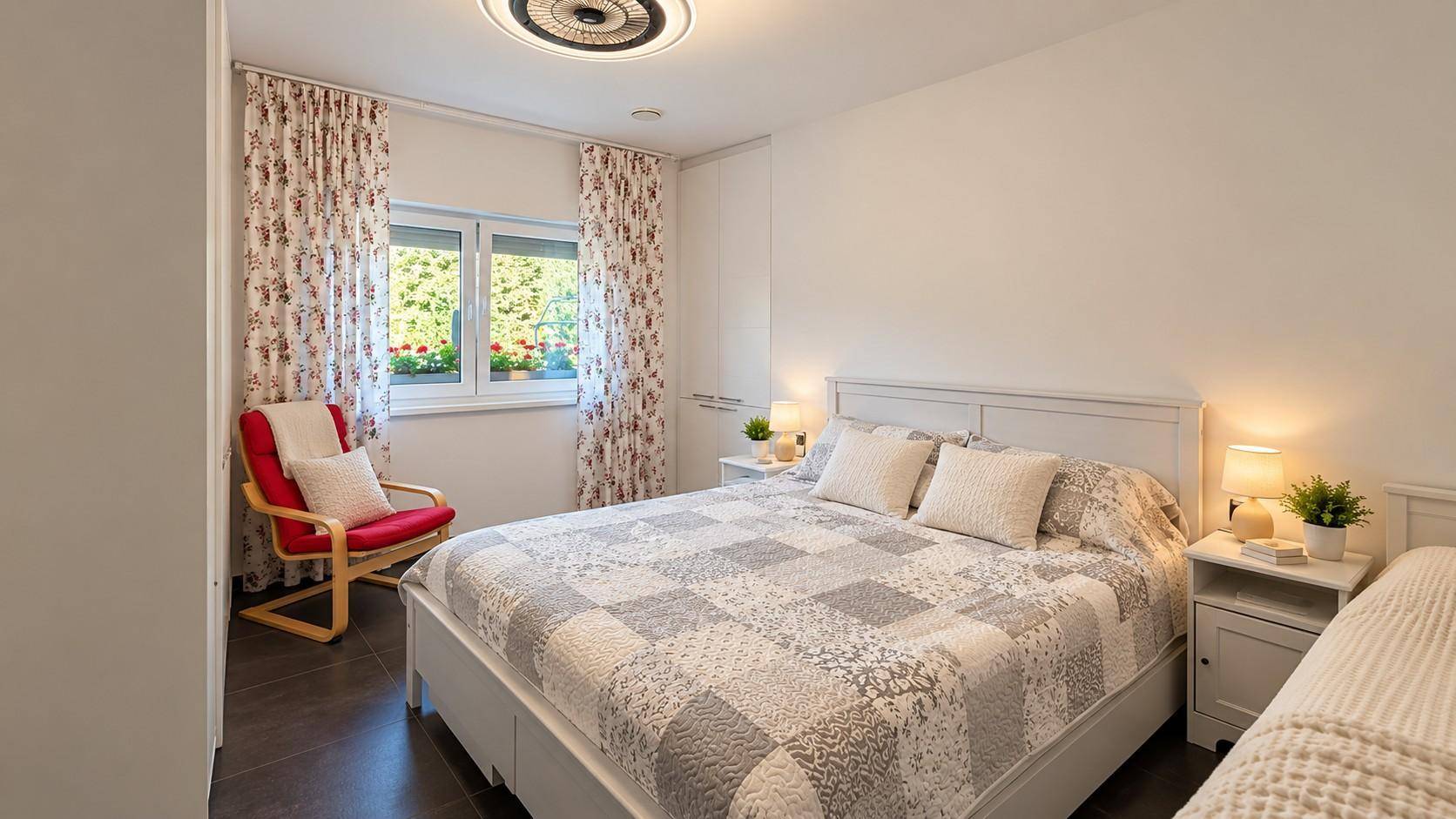 Helles Schlafzimmer mit großem Bett, Nachttischen und Blick ins Grüne.