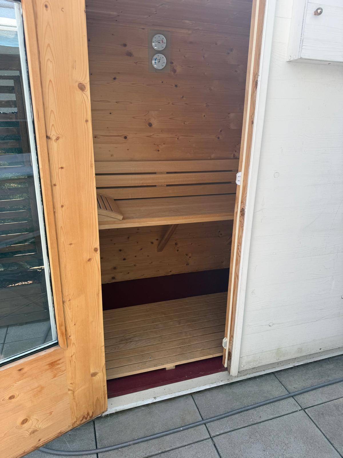 Holzkabine einer Sauna auf der Terrasse mit Blick nach draußen.