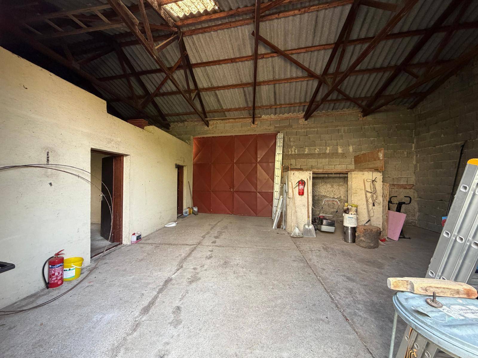 Große Scheune oder Garage mit offenem Dachstuhl und Betonboden.