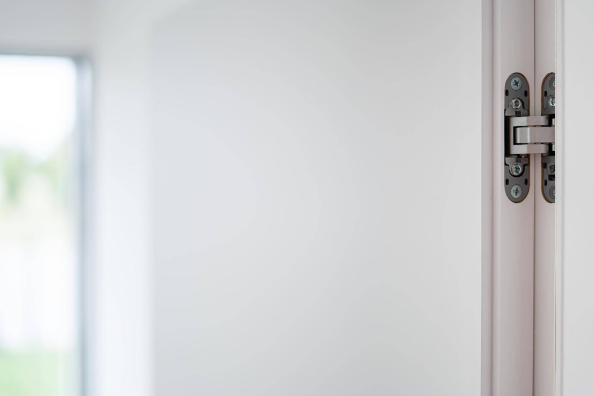 Detailaufnahme eines modernen Türscharniers an einer weißen Innentür.