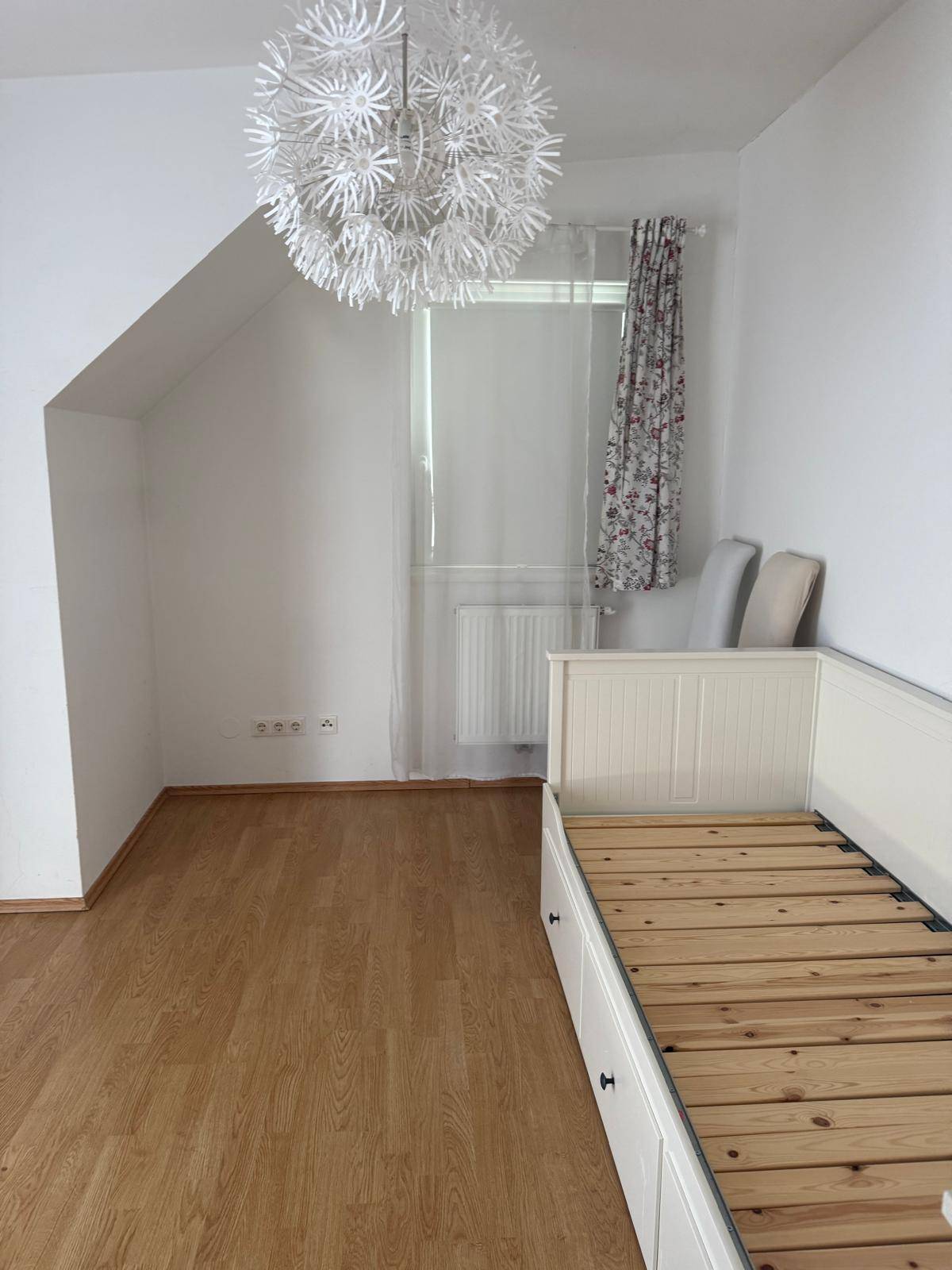 Schlafzimmer mit Dachschräge, Einzelbett und hellem Laminatboden.