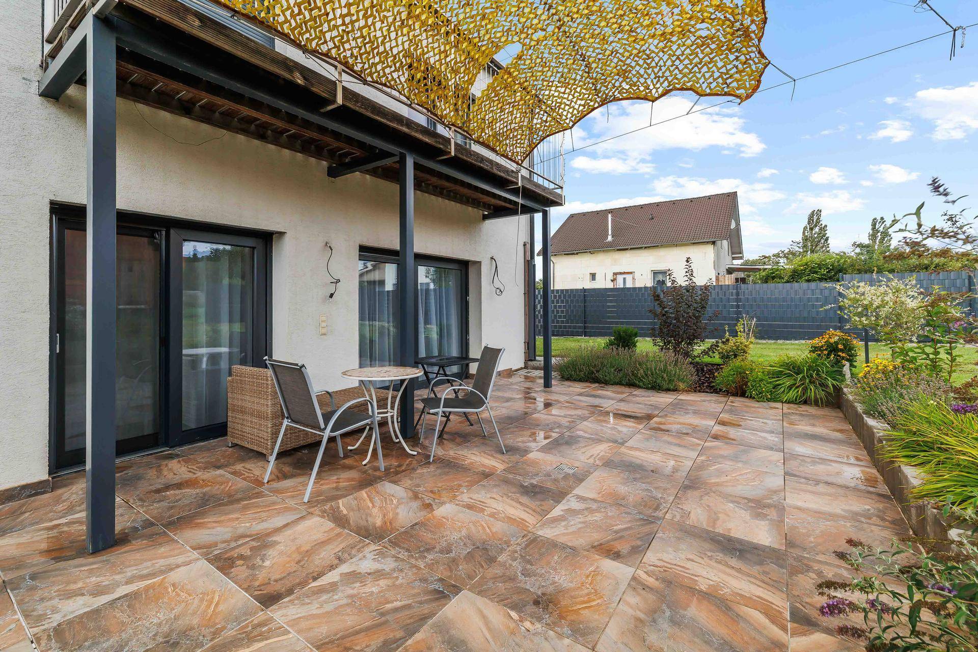 Geräumige Terrasse mit Fliesenboden und Sitzgelegenheiten, ideal für entspannte Stunden im Freien.