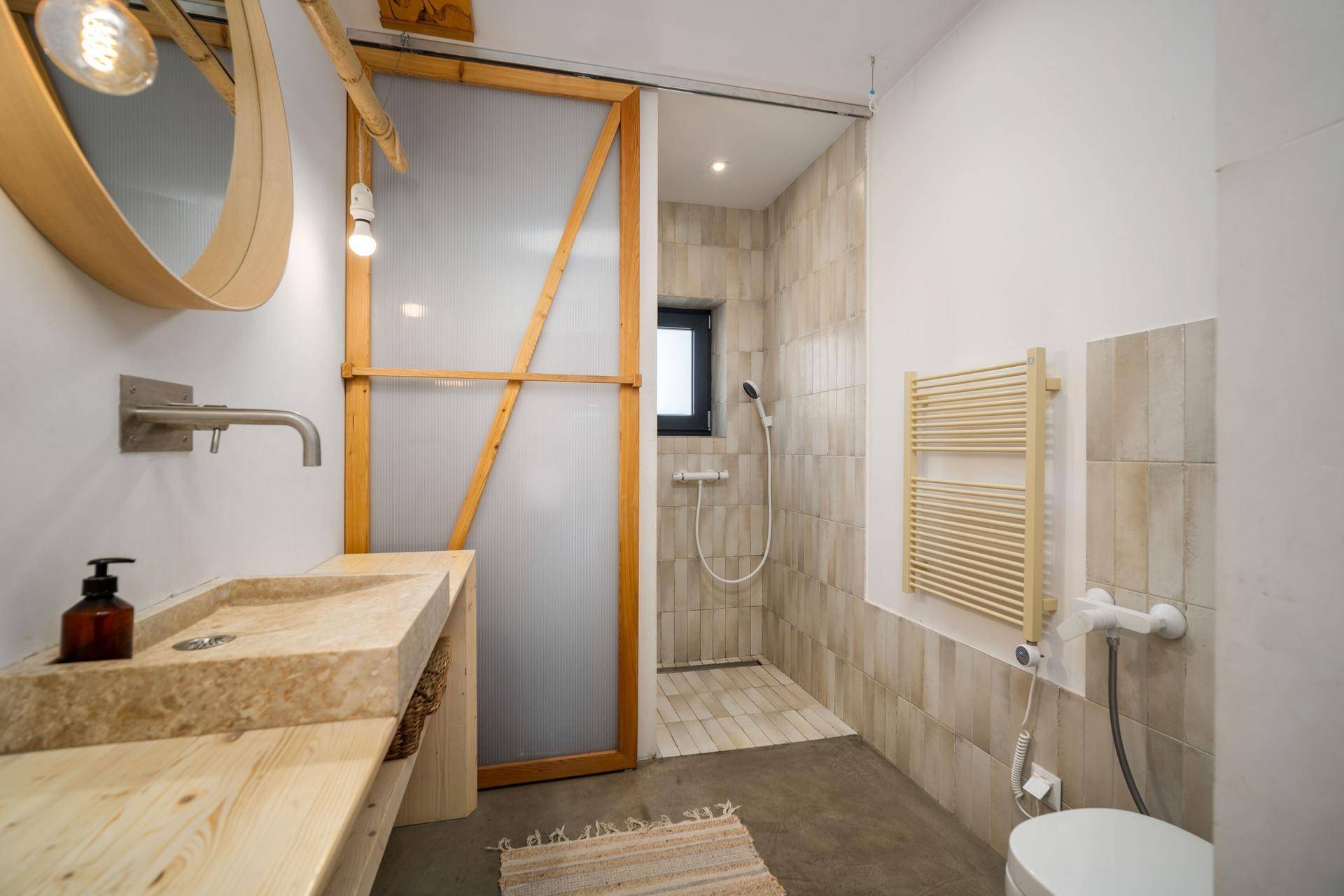 Modernes Badezimmer mit begehbarer Dusche, Natursteinwaschbecken und Holzdetails.