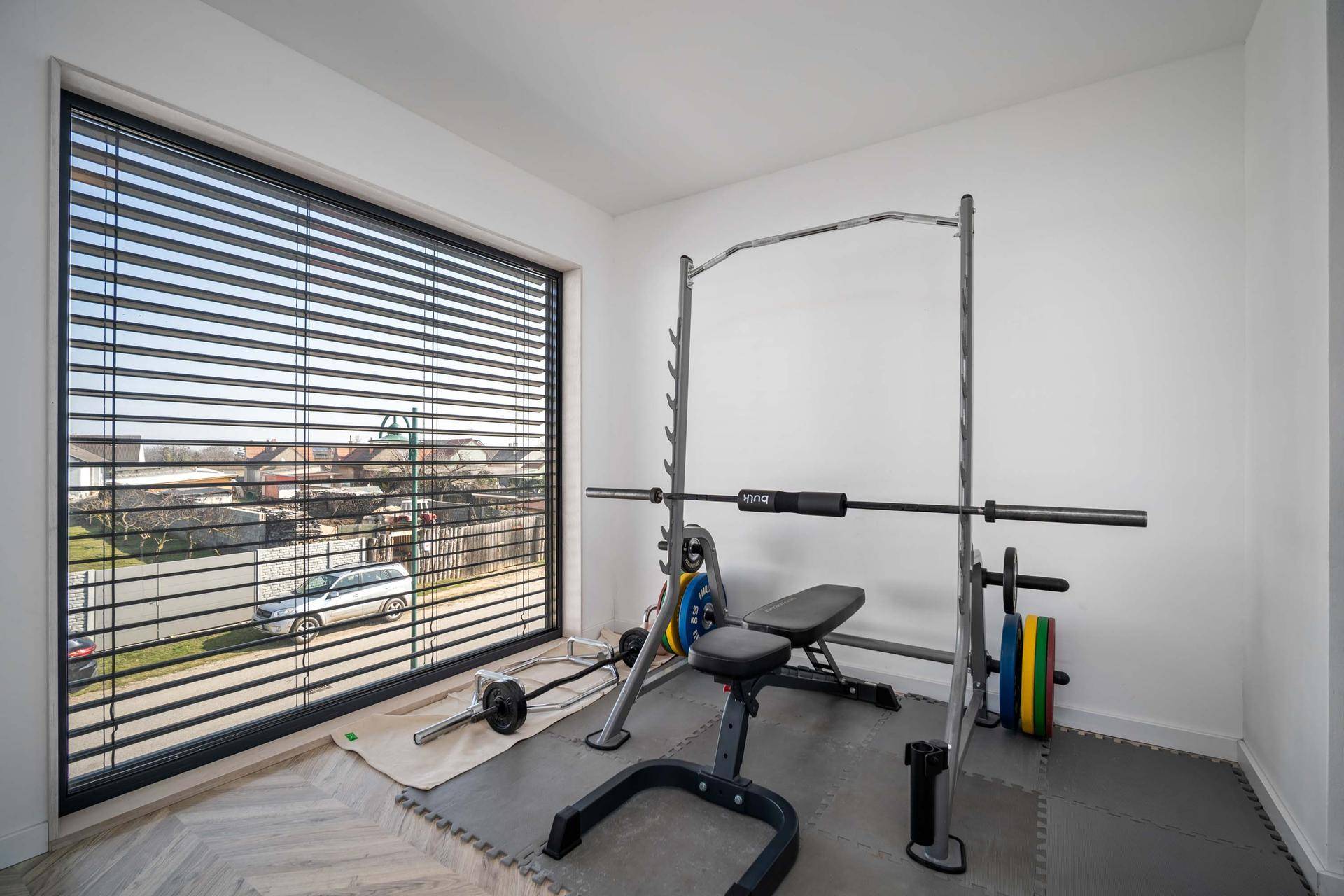 Fitnessraum mit Sportgeräten und großem Fenster für viel Tageslicht.