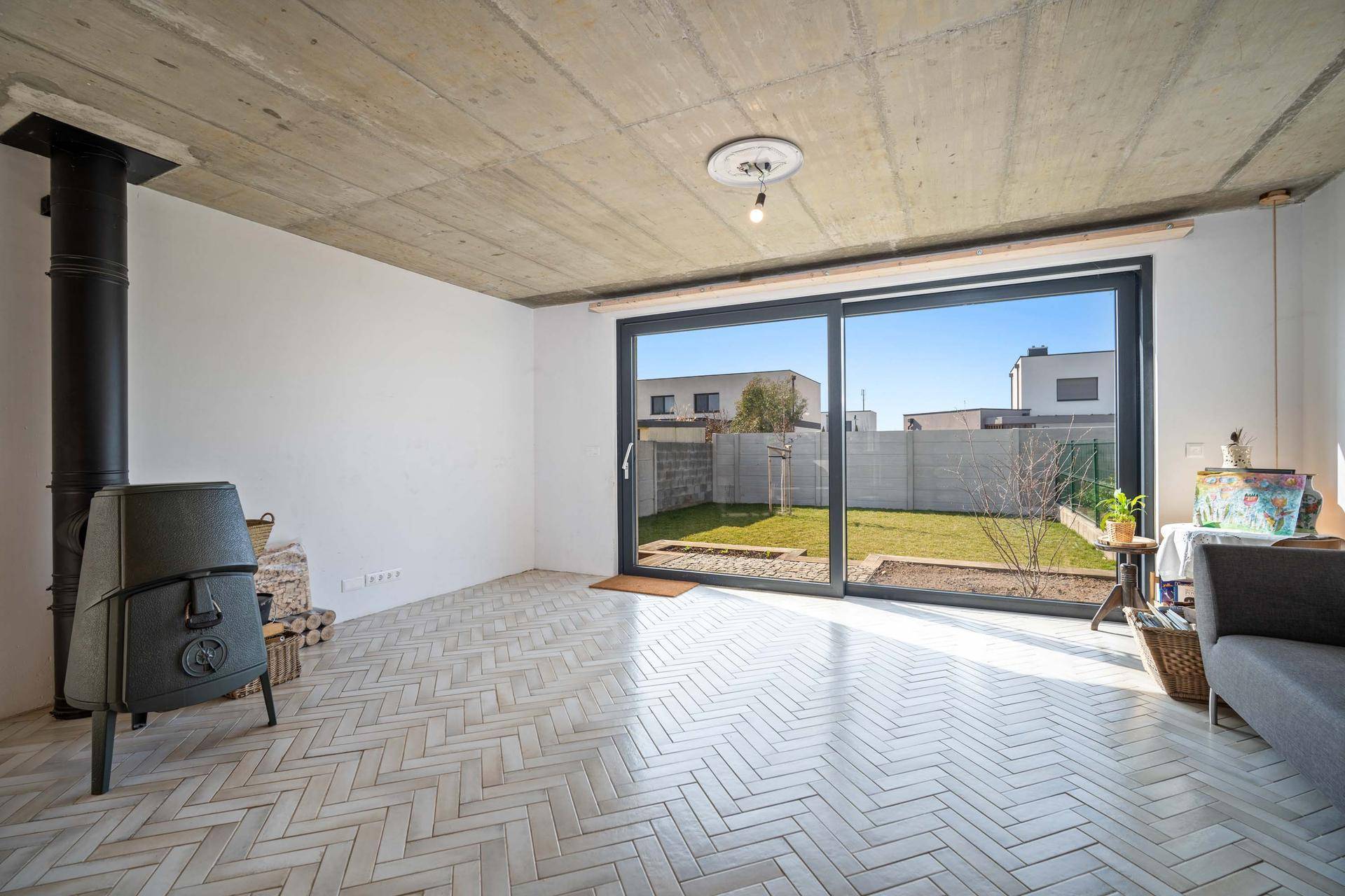 Helles Wohnzimmer mit Kaminofen, großen Schiebetüren und Blick in den Garten.