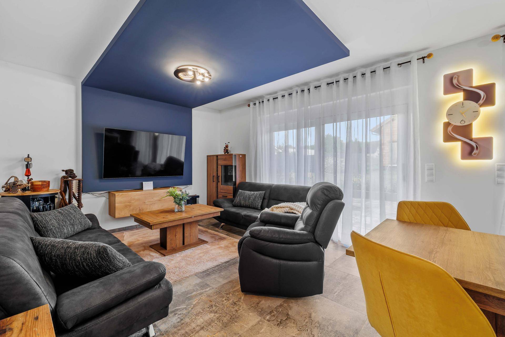 Geräumiger Wohn-Essbereich mit großen Fenstern, bequemen Sitzgelegenheiten und moderner Dekoration.