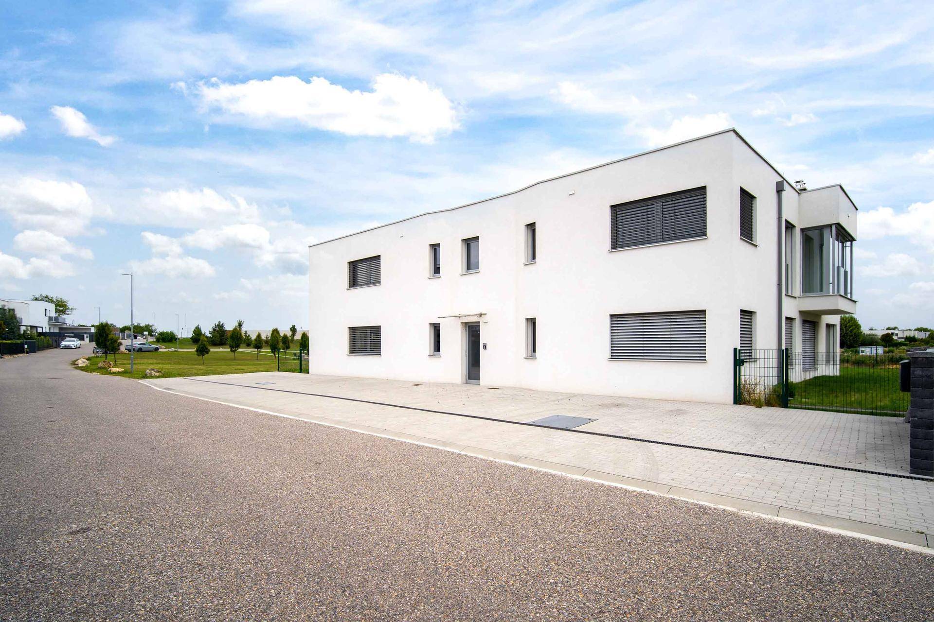 Vorderansicht eines modernen Wohngebäudes mit minimalistischer Fassade und Zufahrt.