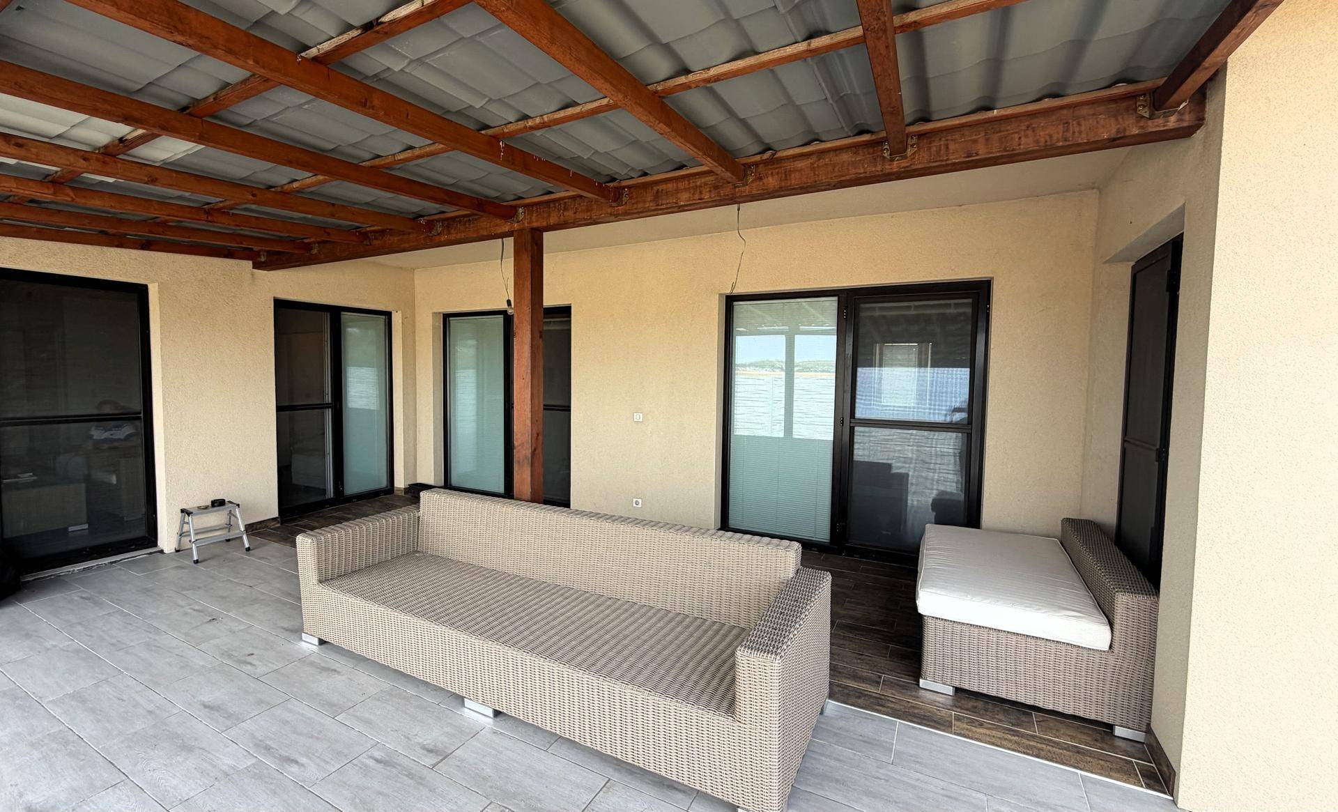 Überdachte Terrasse mit Outdoor-Sofa und Fliesenboden.
