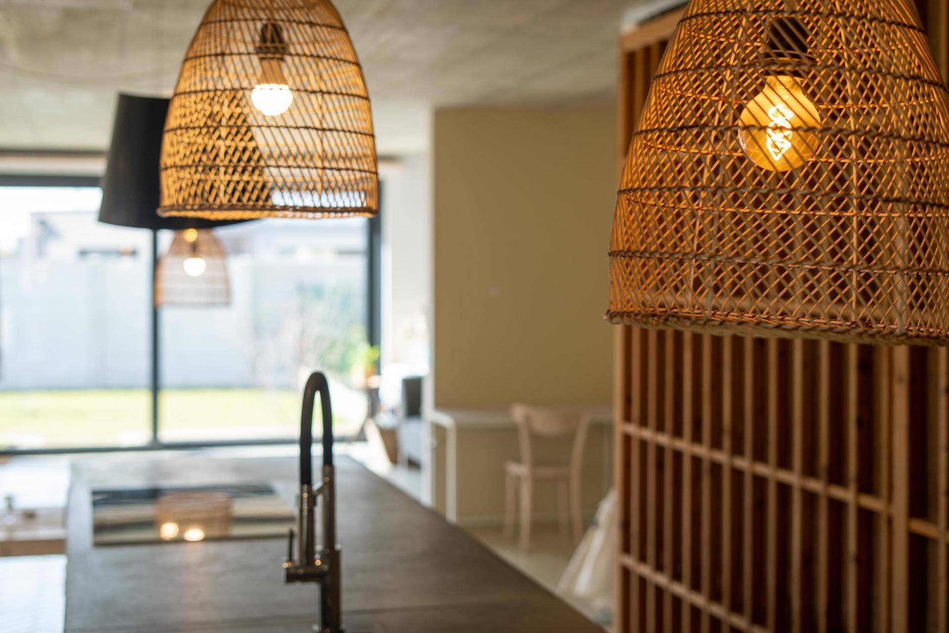 Rattan-Pendelleuchten über der Kücheninsel, die eine warme Atmosphäre schaffen.