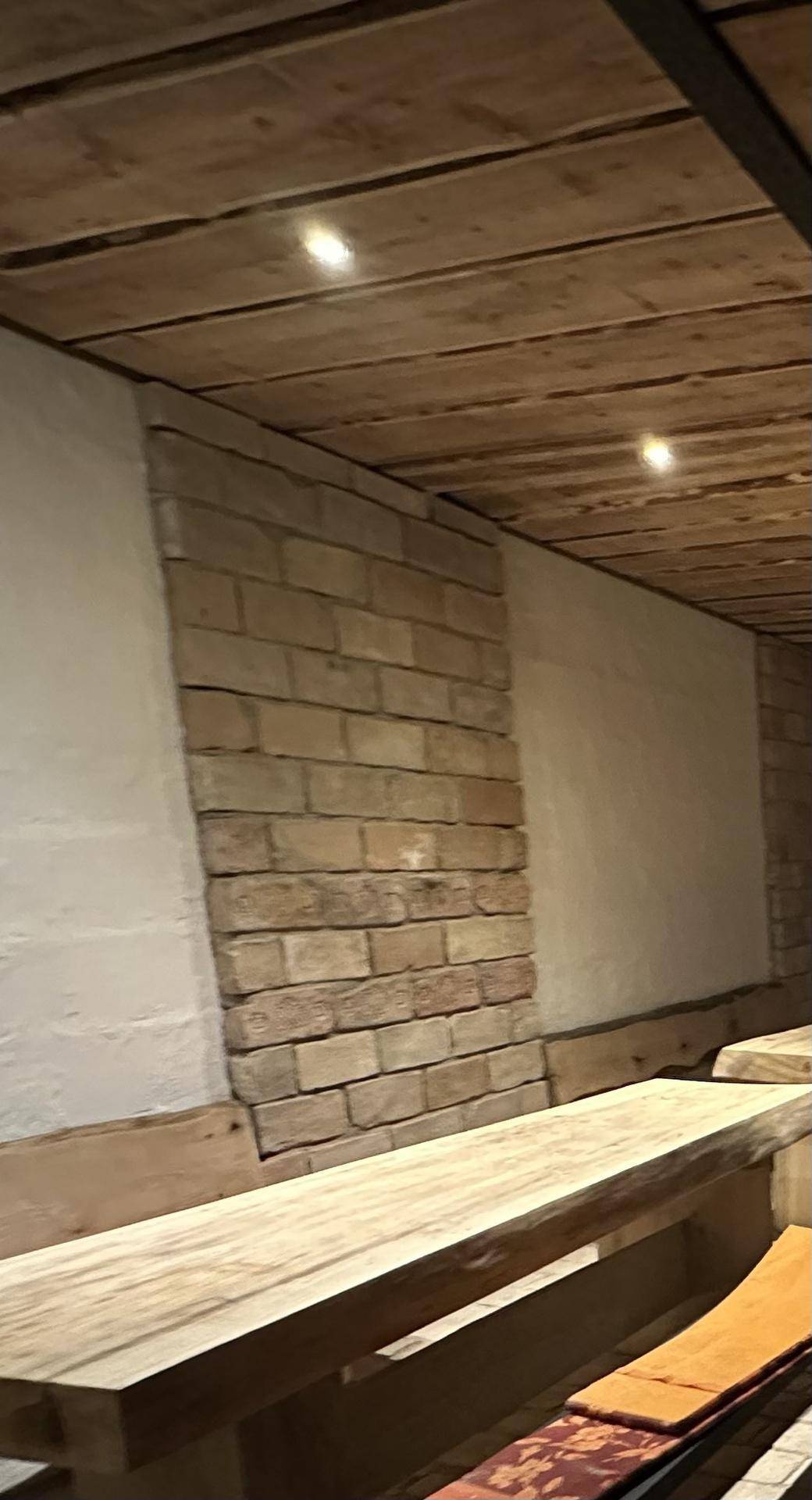 Rustikaler Raum mit Holzdecken, weiß getünchten Wänden und freiliegenden Ziegelakzenten.