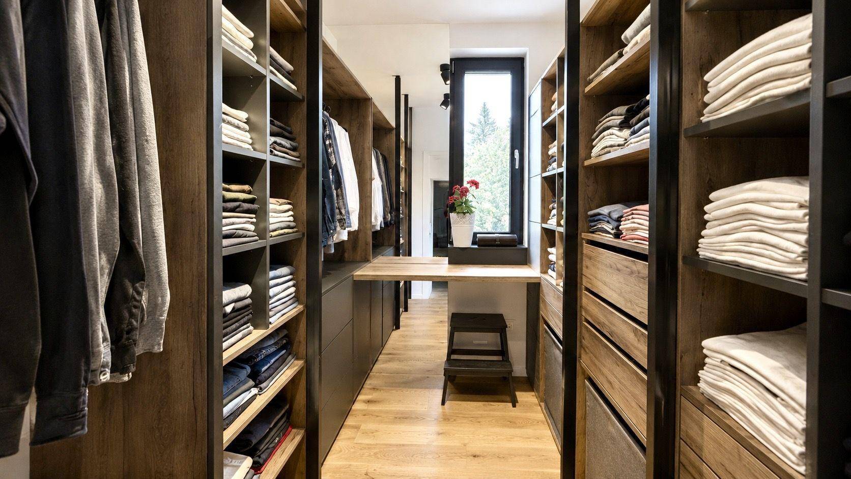 Geräumiger begehbarer Kleiderschrank mit Holzregalen, Schubladen und viel Stauraum.