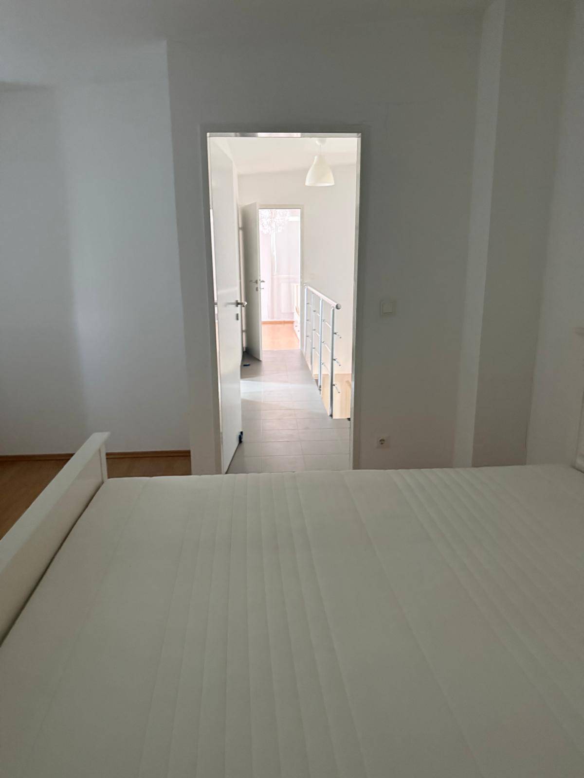 Helles Schlafzimmer mit Doppelbett und Blick in den Flur.