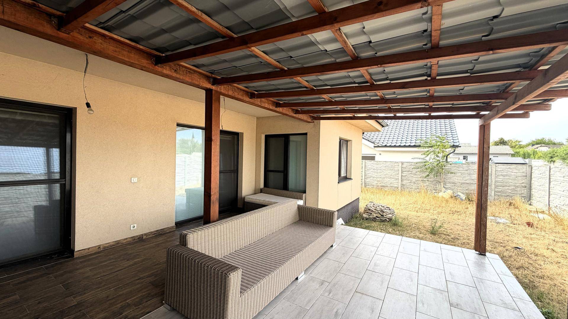 Geräumige überdachte Terrasse mit Sitzgelegenheiten und Blick auf den Garten.