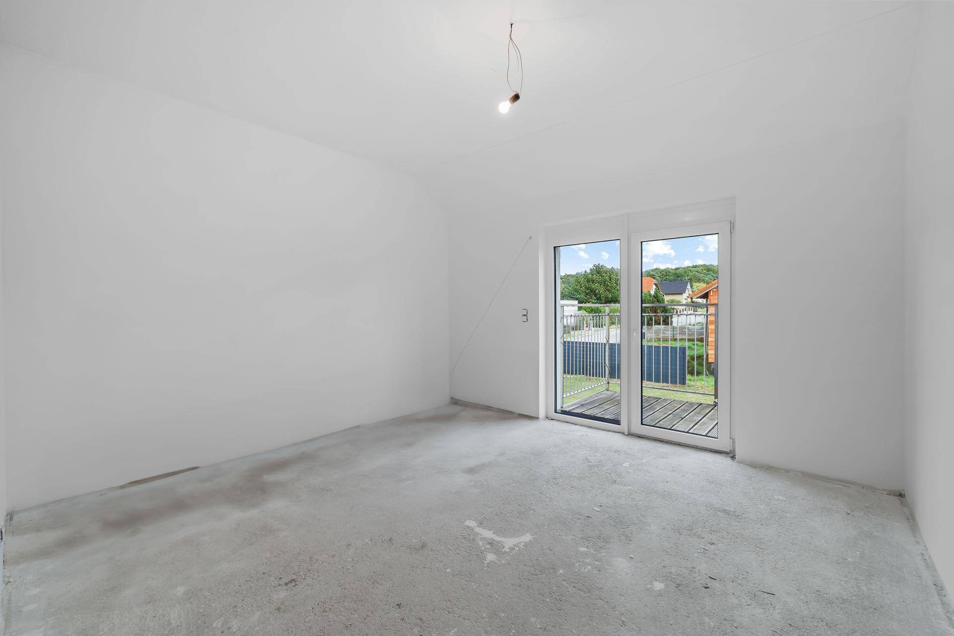 Leeres Schlafzimmer mit Balkonzugang und Blick auf die Umgebung, bereit zur Gestaltung.