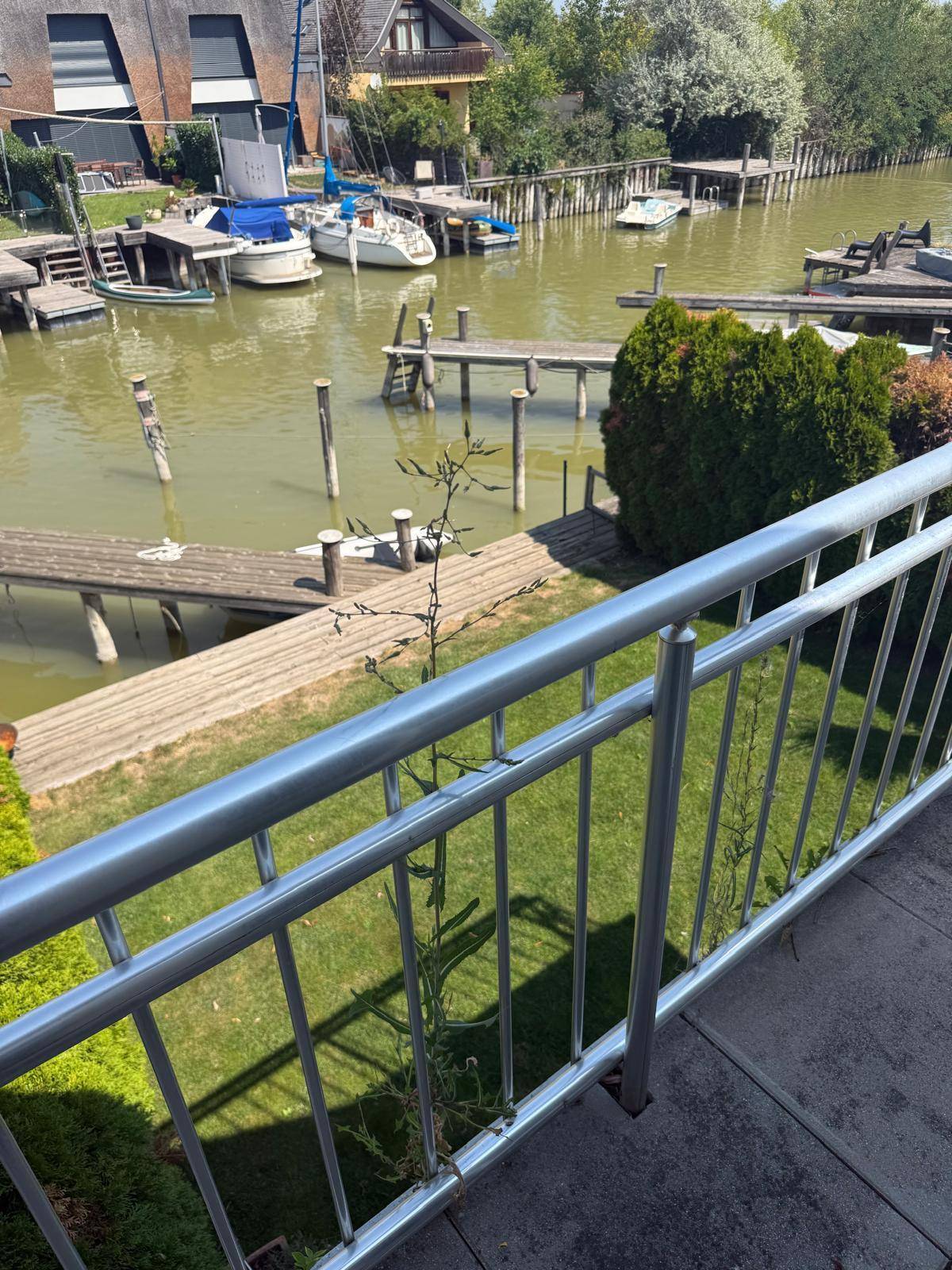Blick vom Balkon auf den Garten und den Kanal mit weiteren Bootsstegen.