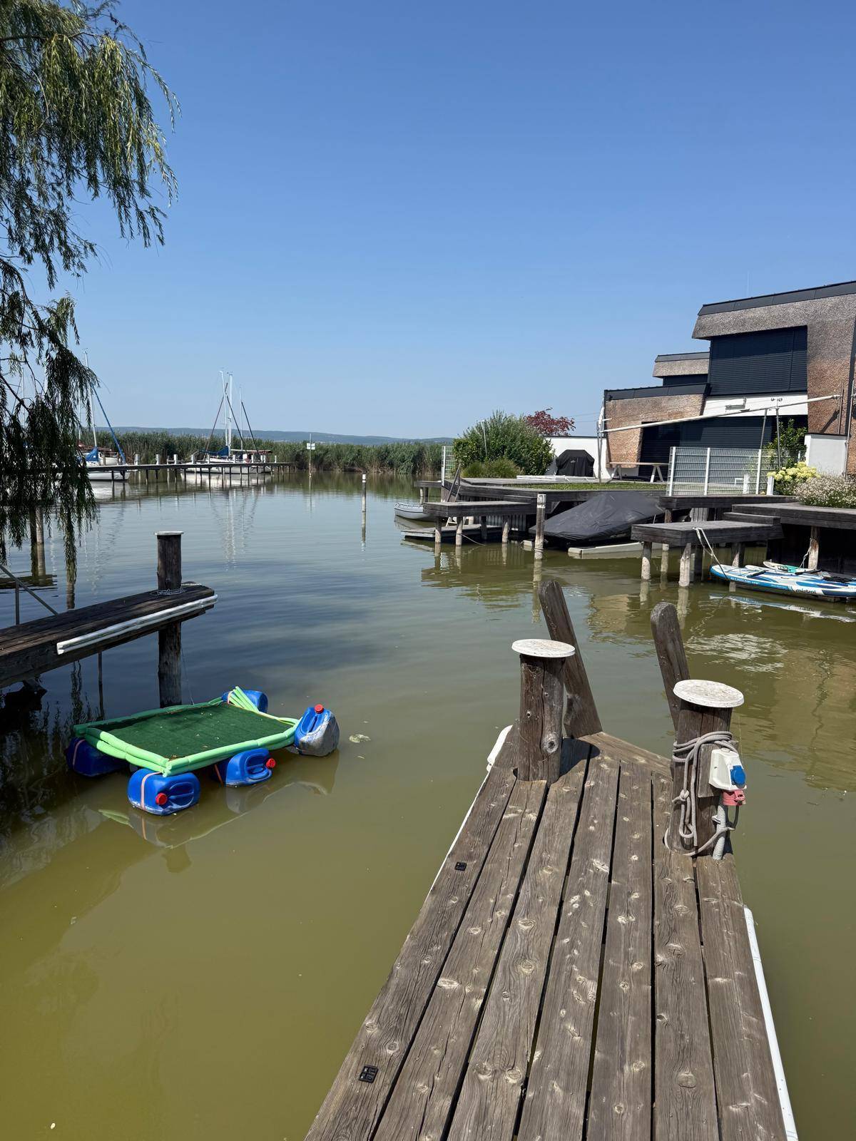 Weitläufiger Blick über den Kanal mit Bootsstegen und angrenzenden Häusern.