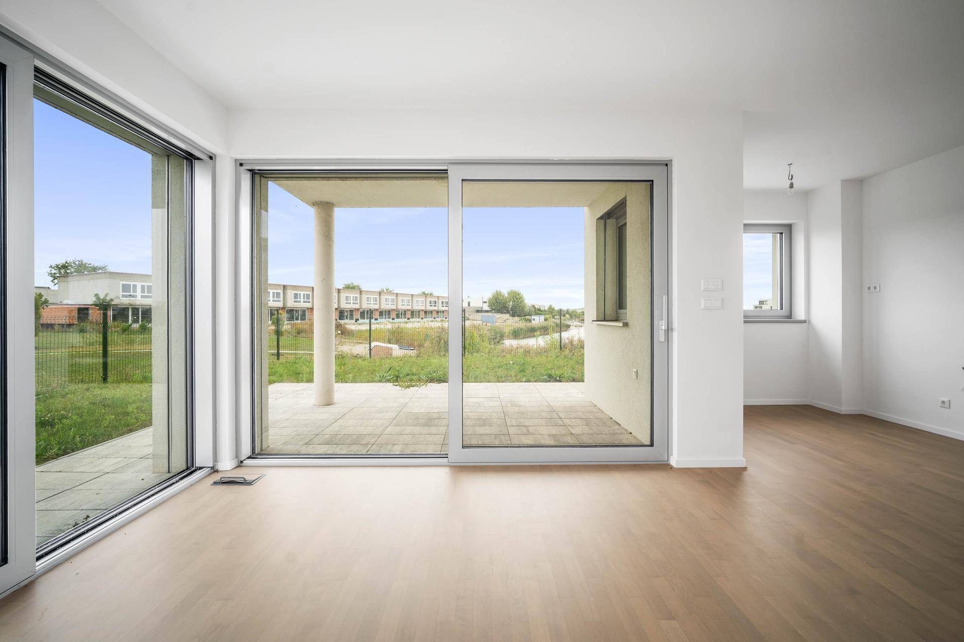 Geräumiges Wohnzimmer mit hellem Parkettboden und direktem Zugang zur Terrasse.