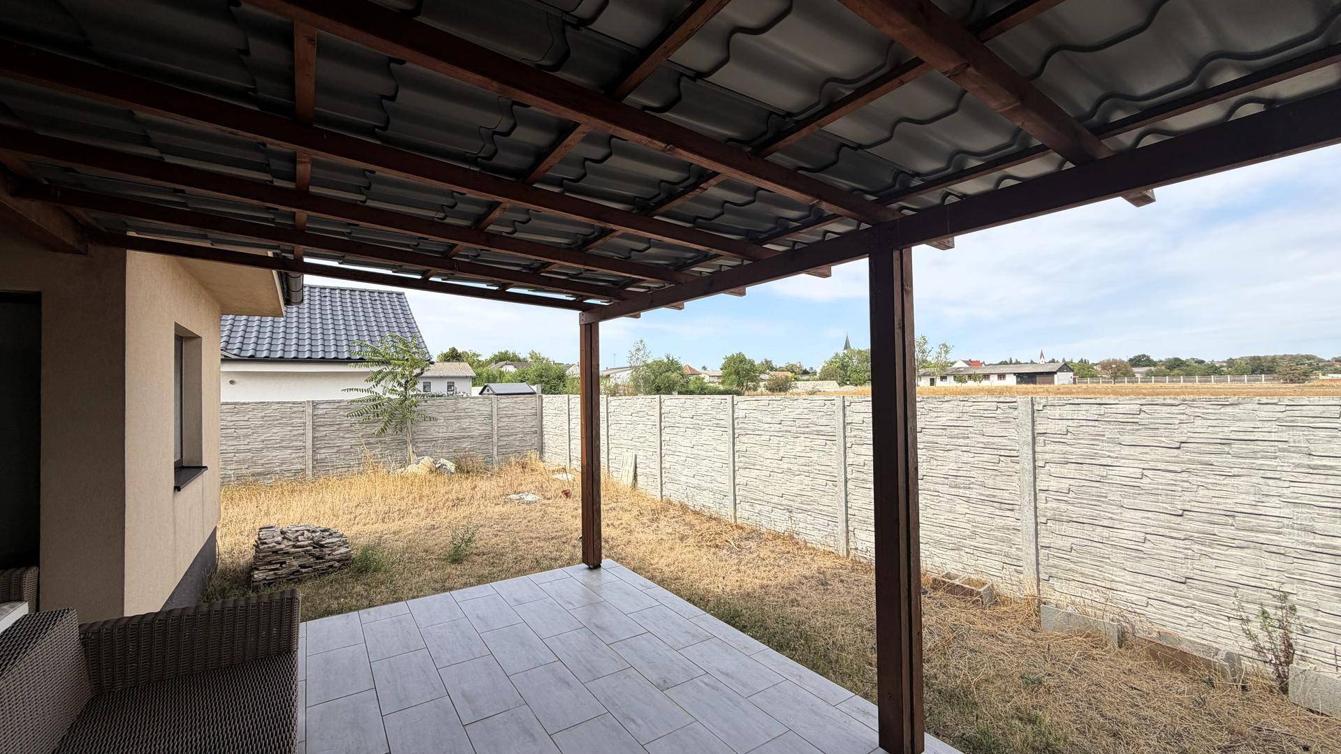 Überdachter Terrassenbereich mit Fliesenboden und Blick auf den Garten.