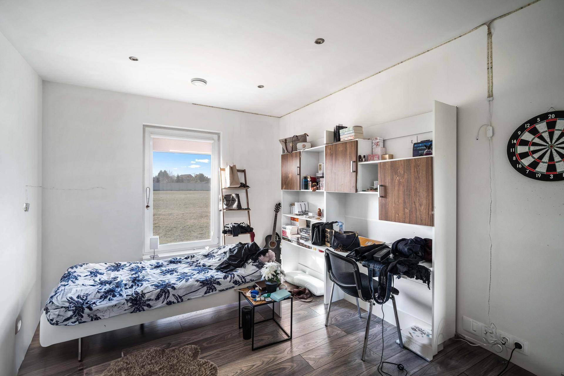 Helles Schlafzimmer mit Fensterblick ins Grüne und funktionalen Regalsystemen.