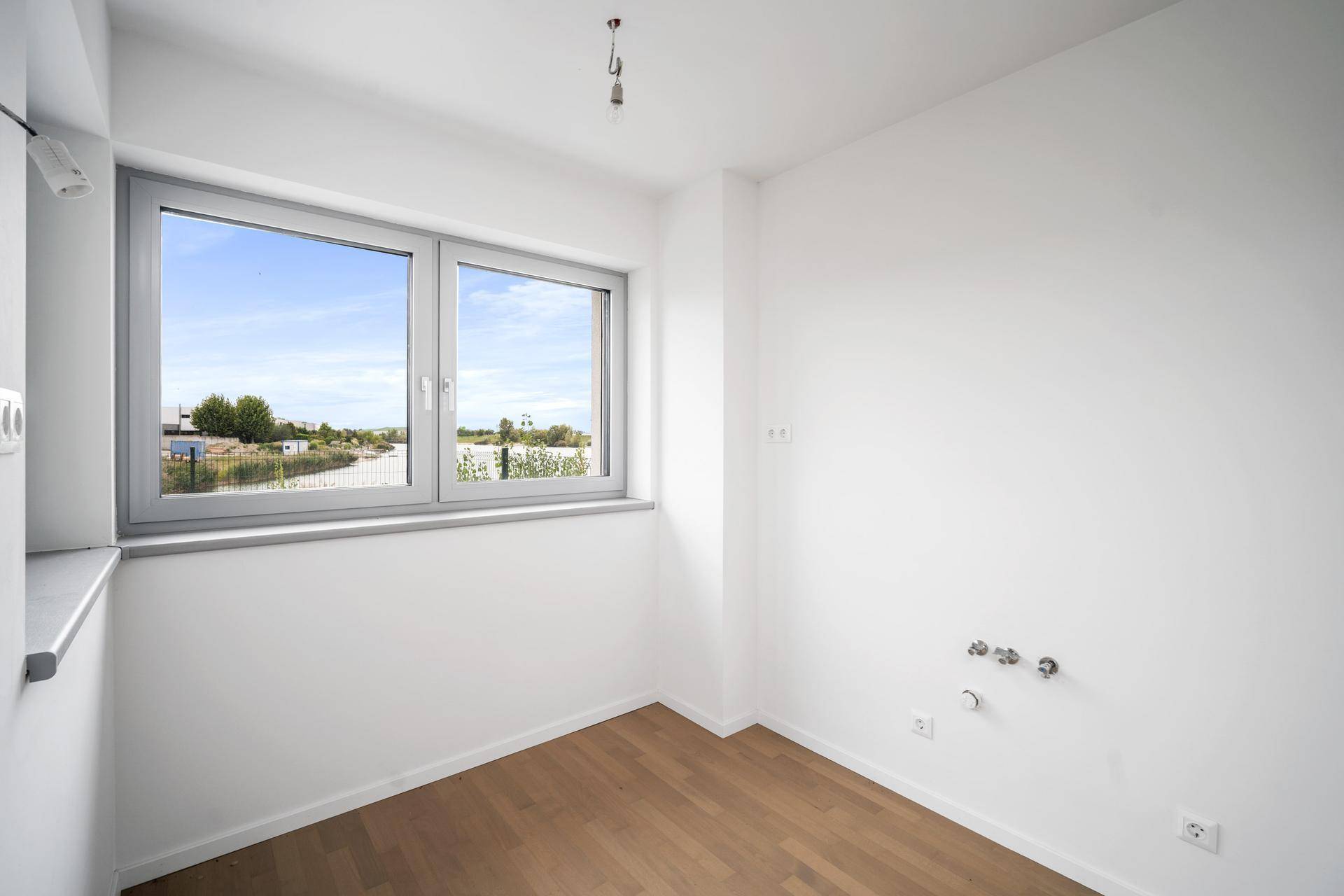 Heller Raum mit Fenster und Anschlüssen, ideal als Hauswirtschaftsraum oder kleine Küche.