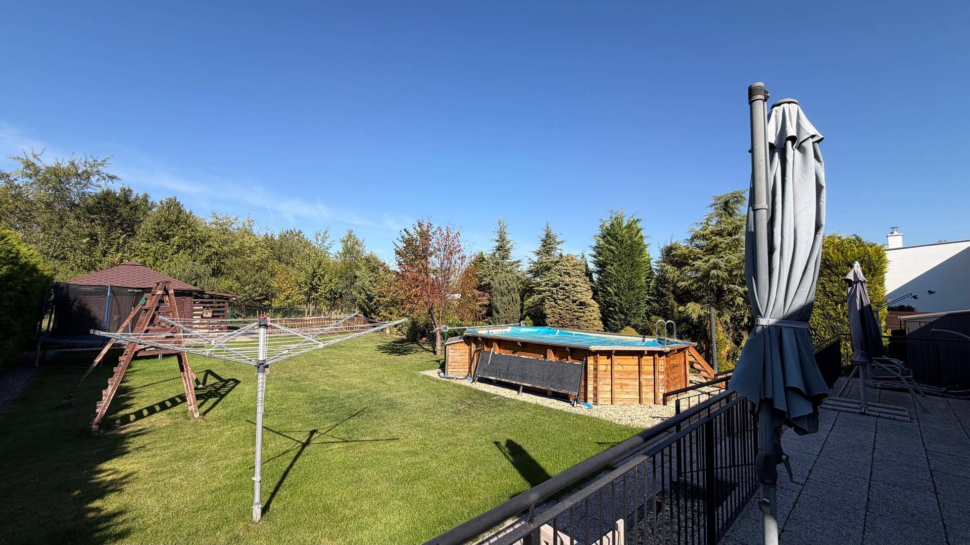 Sonniger Garten mit Pool, Wäscheständer und Blick auf die grüne Umgebung.