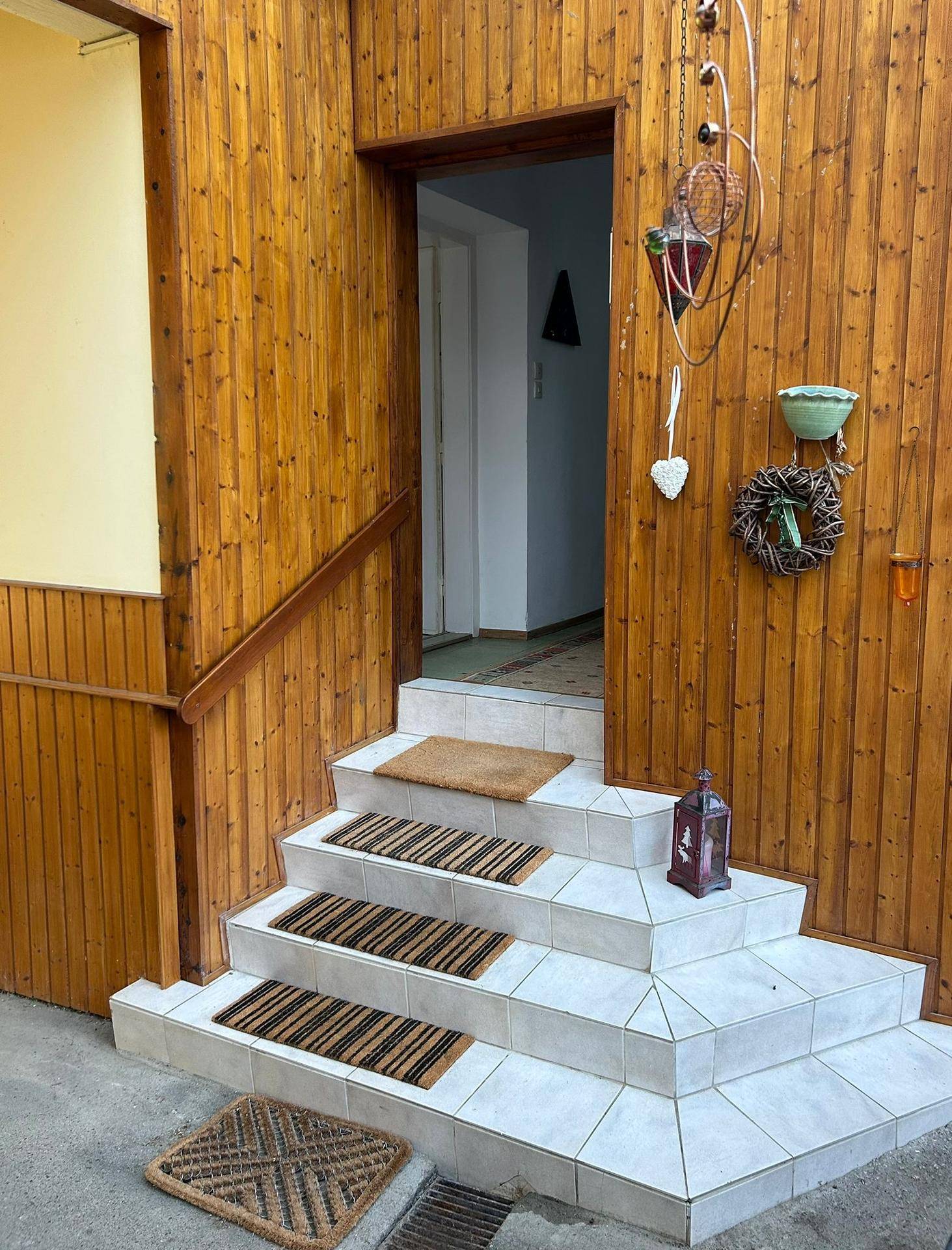 Eingangsbereich mit Holzverkleidung, gefliesten Stufen und rustikalen Dekorationen.