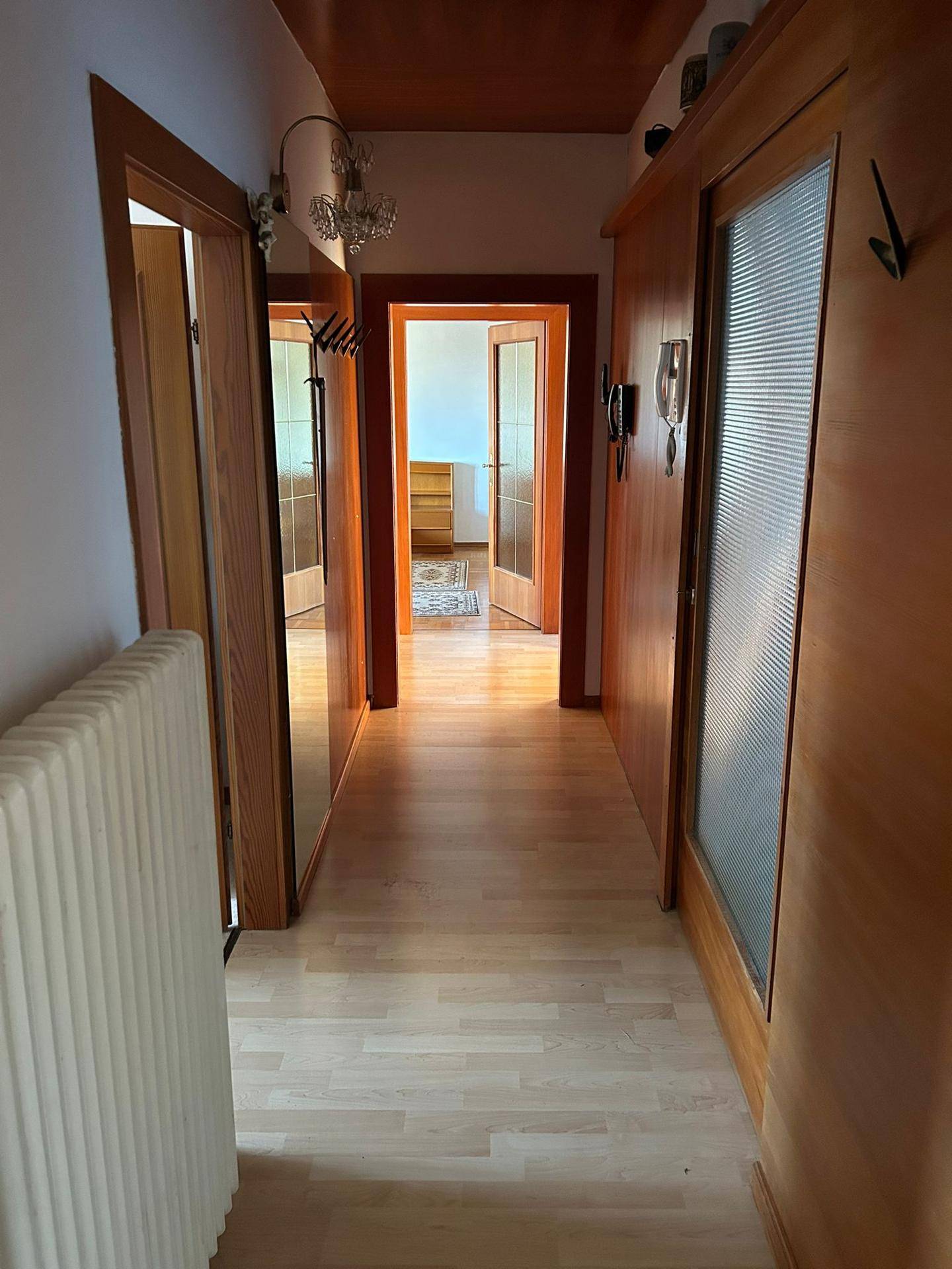 Heller Flur mit Holzfußboden, Holzvertäfelung und Türen zu weiteren Räumen.