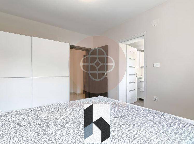 Schlafzimmer mit Doppelbett und weißem Kleiderschrank, angrenzend an ein Badezimmer.