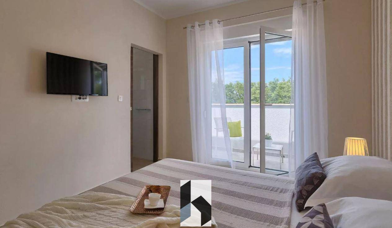 Schlafzimmer mit Wandfernseher und direktem Zugang zu einem möblierten Balkon.