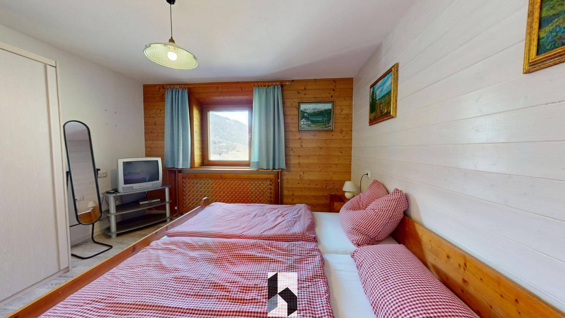 Gemütliches Schlafzimmer mit Doppelbett, Holzvertäfelung und traditioneller Einrichtung, sehr einladend.