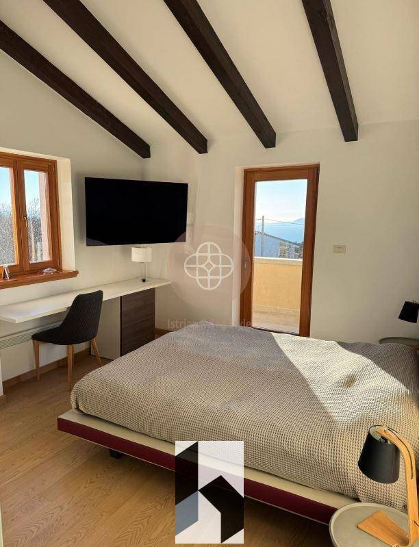 Schlafzimmer mit Holzbalken, Holzboden und Zugang zu einem Balkon mit Aussicht.