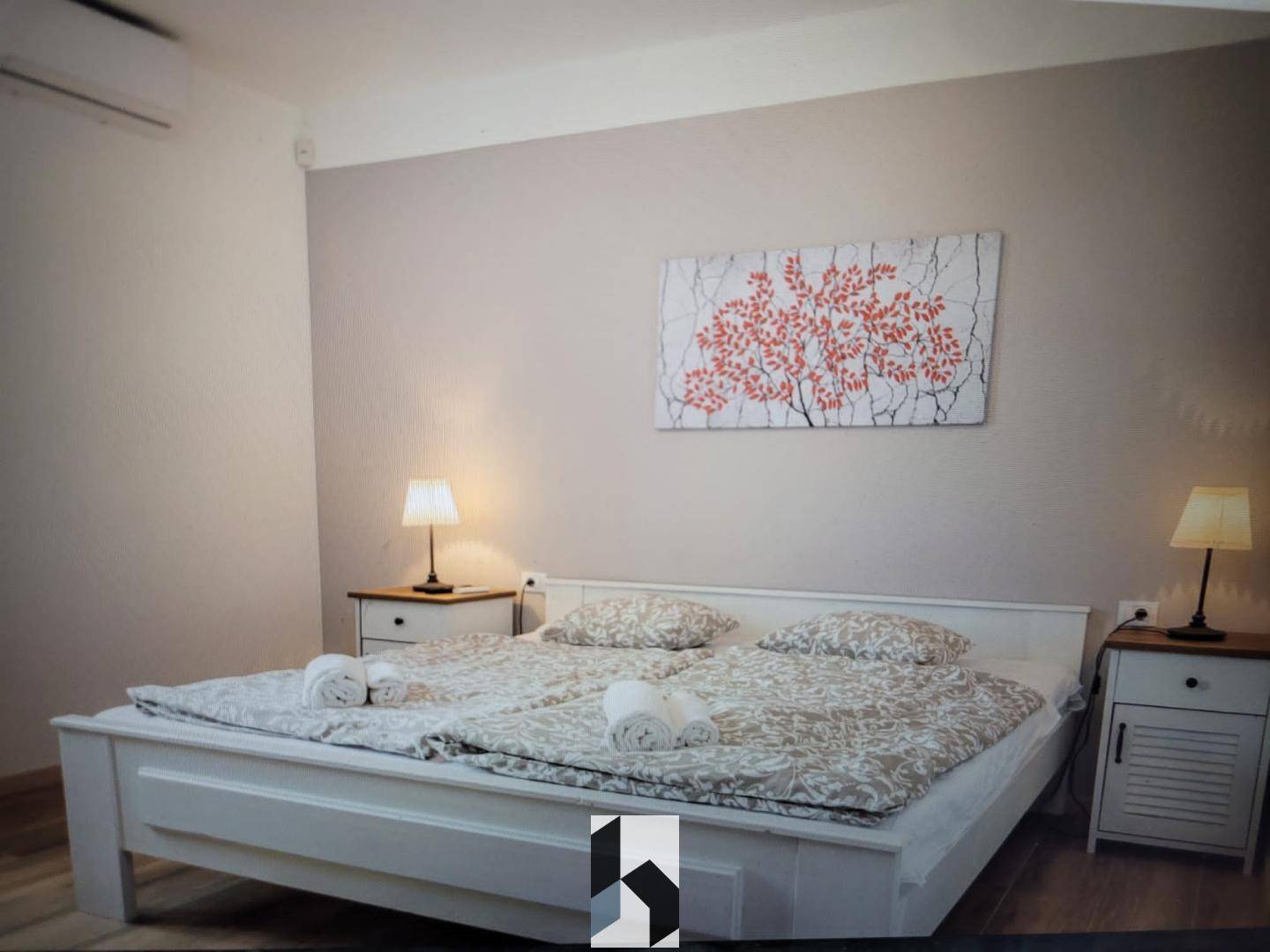 Helles Schlafzimmer mit Doppelbett, Nachttischen und dekorativem Wandbild.
