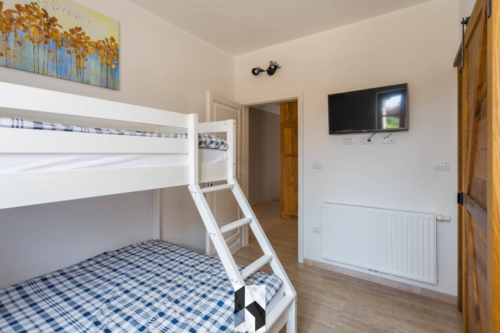 Kinderfreundliches Schlafzimmer mit Etagenbett und Fernseher an der Wand.