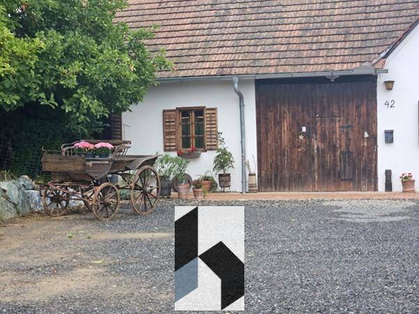 Detailansicht des Landhauses mit rustikalem Holzwagen und traditionellen Fensterläden.