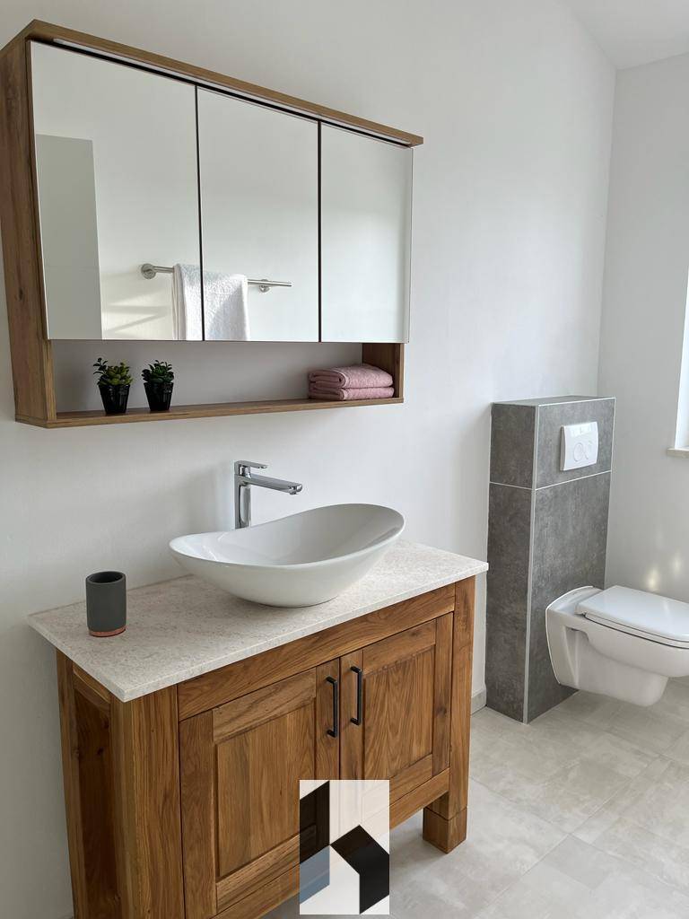 Elegantes Badezimmer mit Aufsatzwaschbecken, Holzunterschrank und Spiegelschrank.